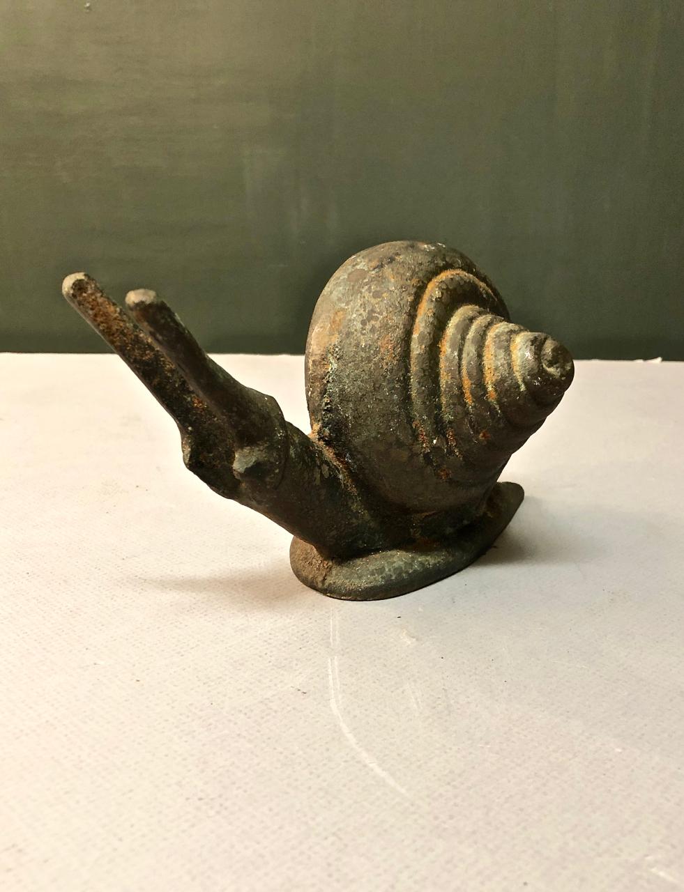 This is a charming cast iron sculpture, possibly a bookend or doorstop, of a garden snail. The snail exhibits lots of character, making it a great decorative element.