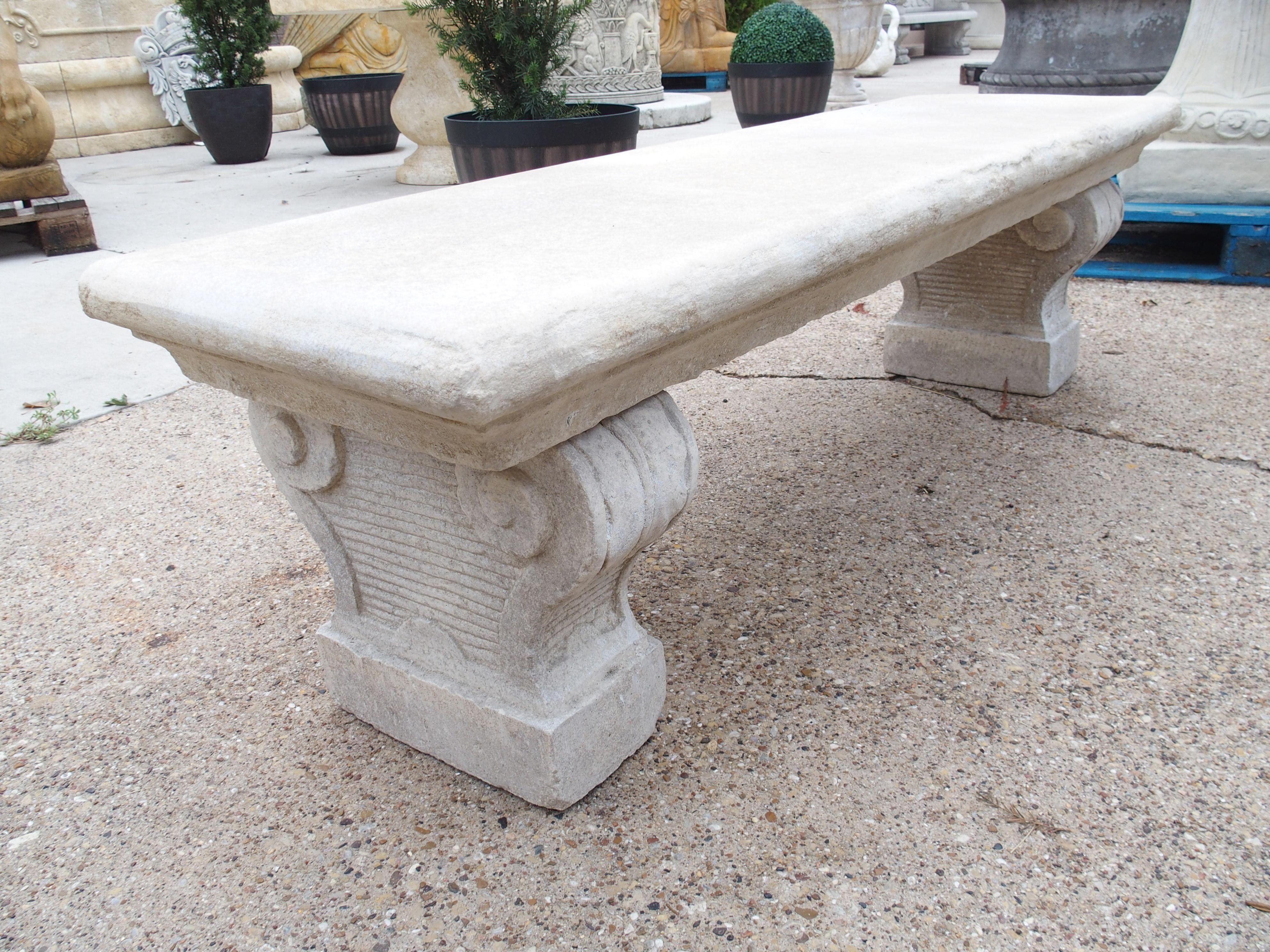 Consisting of reconstituted limestone, this garden bench was cast in Southern Italy. All three pieces of stone have a cream-colored finish with areas of white accents. The four-inch thick seat has been given a cavetto molding on all four sides,