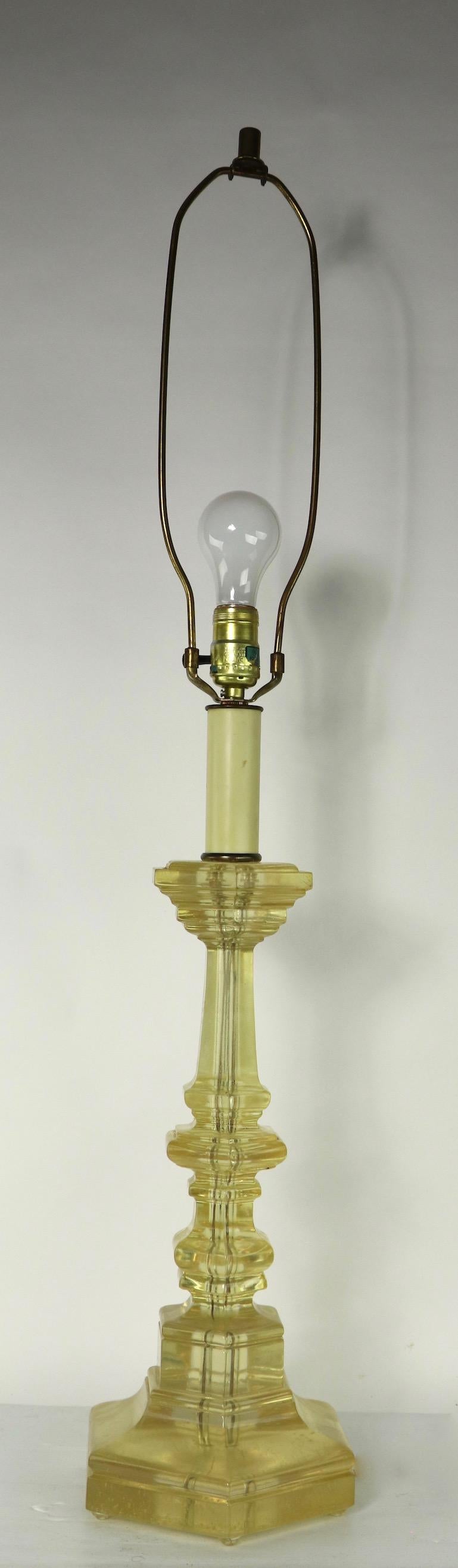 Chic and stylish table lamp in the form of a candlestick, in solid cast lucite. This example is in good originalm and working condition, it has a small impact bruise, and is missing one foot at the base, both condition issues are inconsequential and