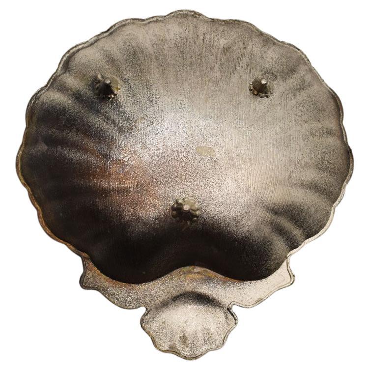 A small cast metal salt dish in the shape of a clam shell. This lovely piece would make a fabulous vide poche, trinket dish, or catchall. Created from cast metal, the dish sits upon three faux bois legs. The edges and interior of the dish are