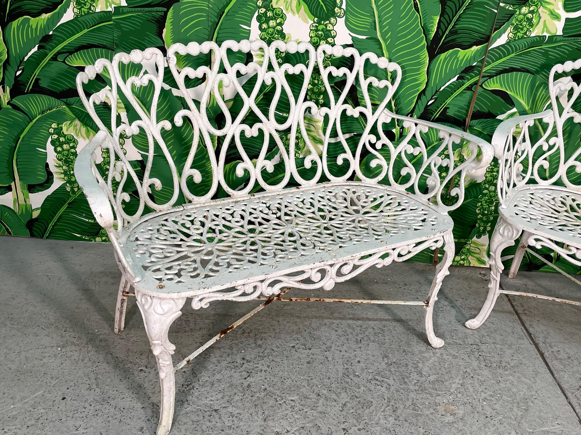 Pair of cast aluminum garden/patio benches in the manner of Frances Elkins. Loveseats or small sofas. Heavy construction, assuming aluminum but possibly iron. Structurally sound with imperfections to the finish (see photos). Seat height measures