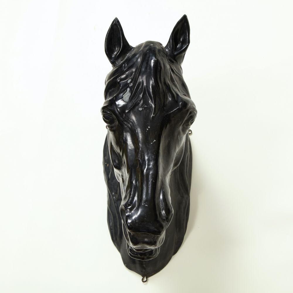 Black enameled horse head originally used as a butcher's trade sign. With mounting hooks on back.