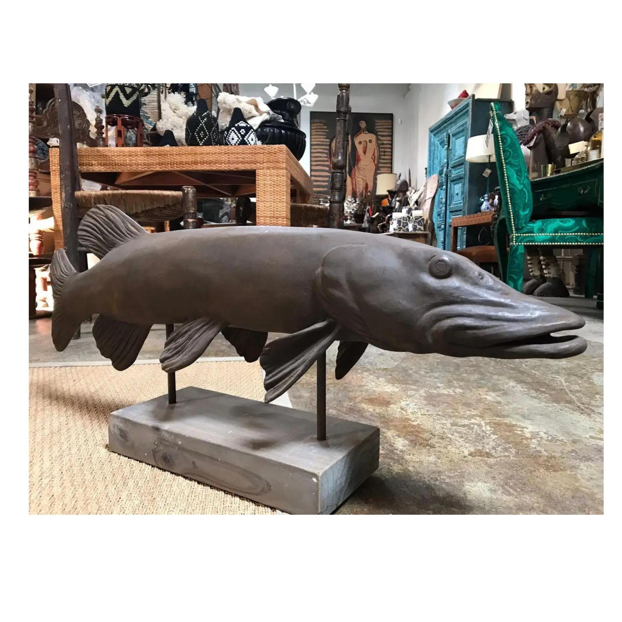 This pike fish sculpture is cast in a light, textured, brown patinated metal and is mounted on a matching grey wood. The details on the fins, face and even the scales are quite distinct and defined.