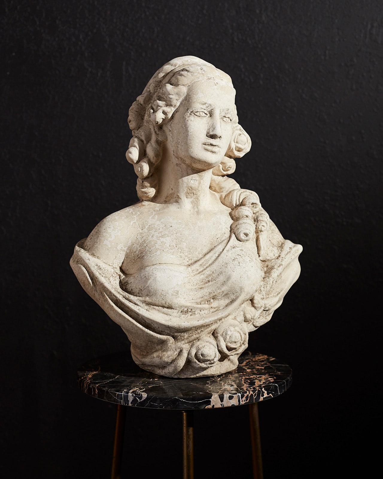 Beautiful cast stone garden bust sculpture of French Queen Marie Antoinette (1755-1793). Very heavy and solid with a lovely distressed patina of an aged marble piece. Depicted with curly locks of hair, roses on her dress and a mesmerizing gaze.