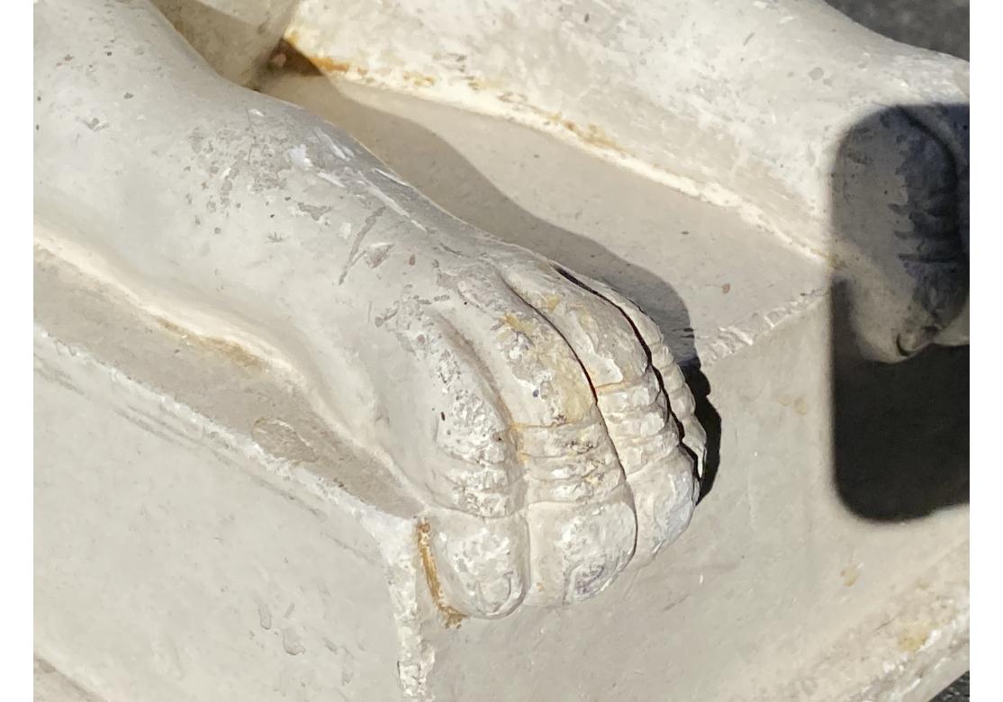 Un'imponente statua in pietra fusa di tipo revival egiziano con un'interpretazione unica di una sfinge greca. La statua presenta un design bifronte con due figure che sfoggiano lunghi copricapi e capelli intrecciati, espressioni neutre, busti