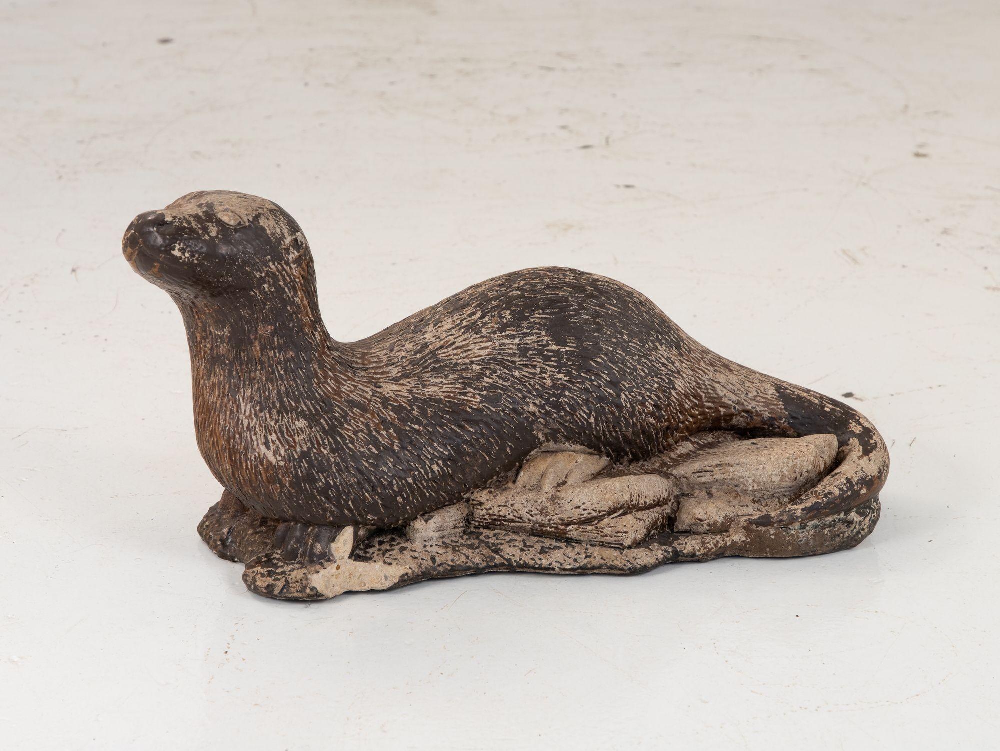 A mid 20th century cast stone English garden ornament in the shape of an otter. The lifelike detail in the coat and the face make for a wonderful example of a classic English garden ornament. The otter retains much of its original brown paint. Some