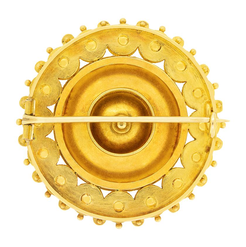 Cette broche Castellani de style néo-archéologique date des années 1870. Le disque circulaire est stylisé comme une tête de fleur avec un grenat au centre, entouré de perles d'émail blanc et de pétales d'émail turquoise. Cette broche comporte