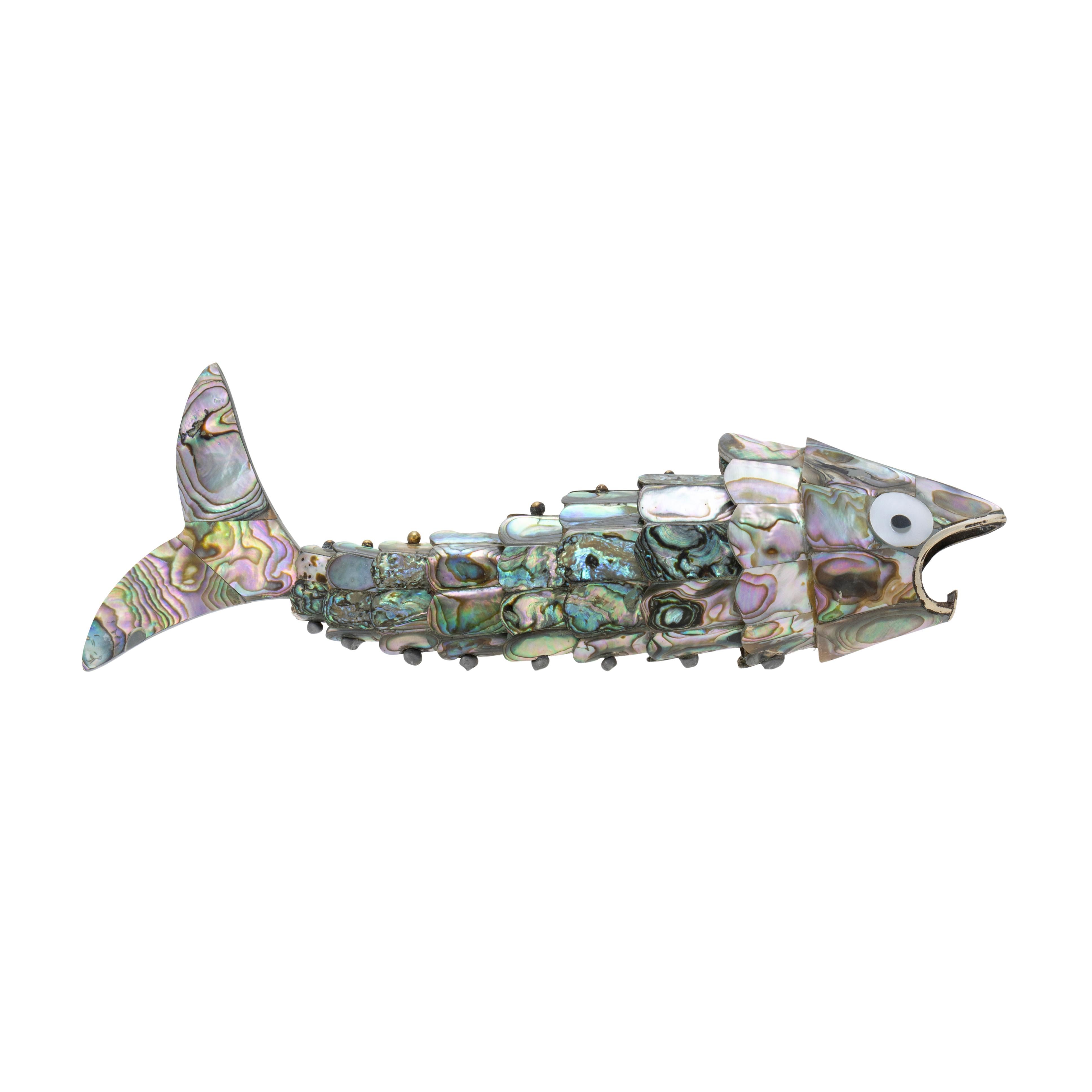 Apribottiglie a forma di pesce in stile Castillo. Il corpo è flessibile e presenta scaglie oscillanti di abalone blu del Pacifico nei colori variegati di rosa, argento, nero, blu e verde. Probabilmente proviene dalla regione di Taxco Mexico, da dove