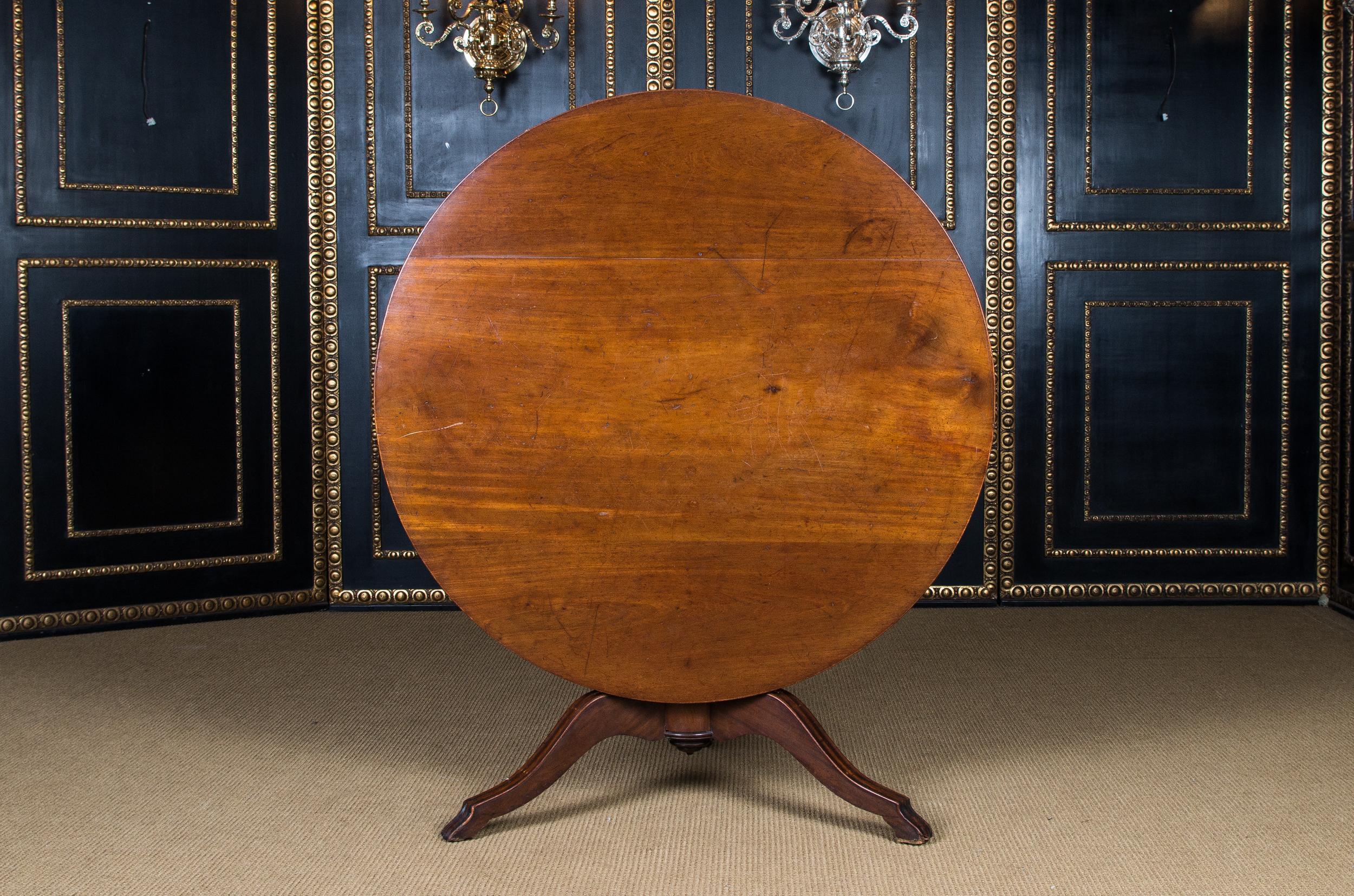 Massive mahogany. Round column shaft, below which are three volute-shaped curved legs. Straight cheeks for round tabletop. The table is equipped with a folding mechanism.

On the reverse stamped K.P for the palace Royal Palace.

Similar table in the