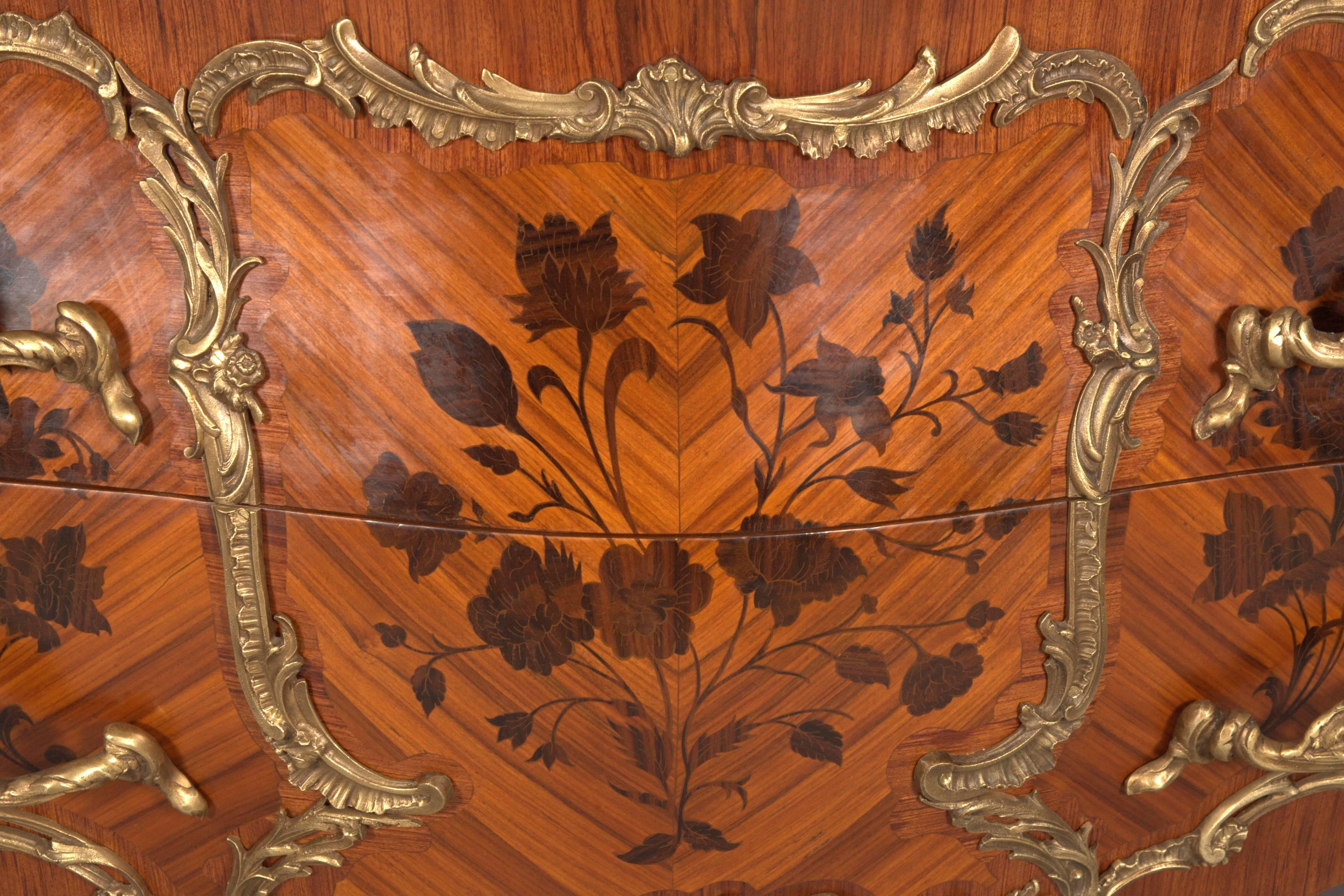 Rosewood and shaded precious wood, veneered. In the front two drawers, in the front and on the side walls broadly framed fillings with richly inlaid blooms of different noble wood, limited by so-called mirror veneer. On the corresponding sides and