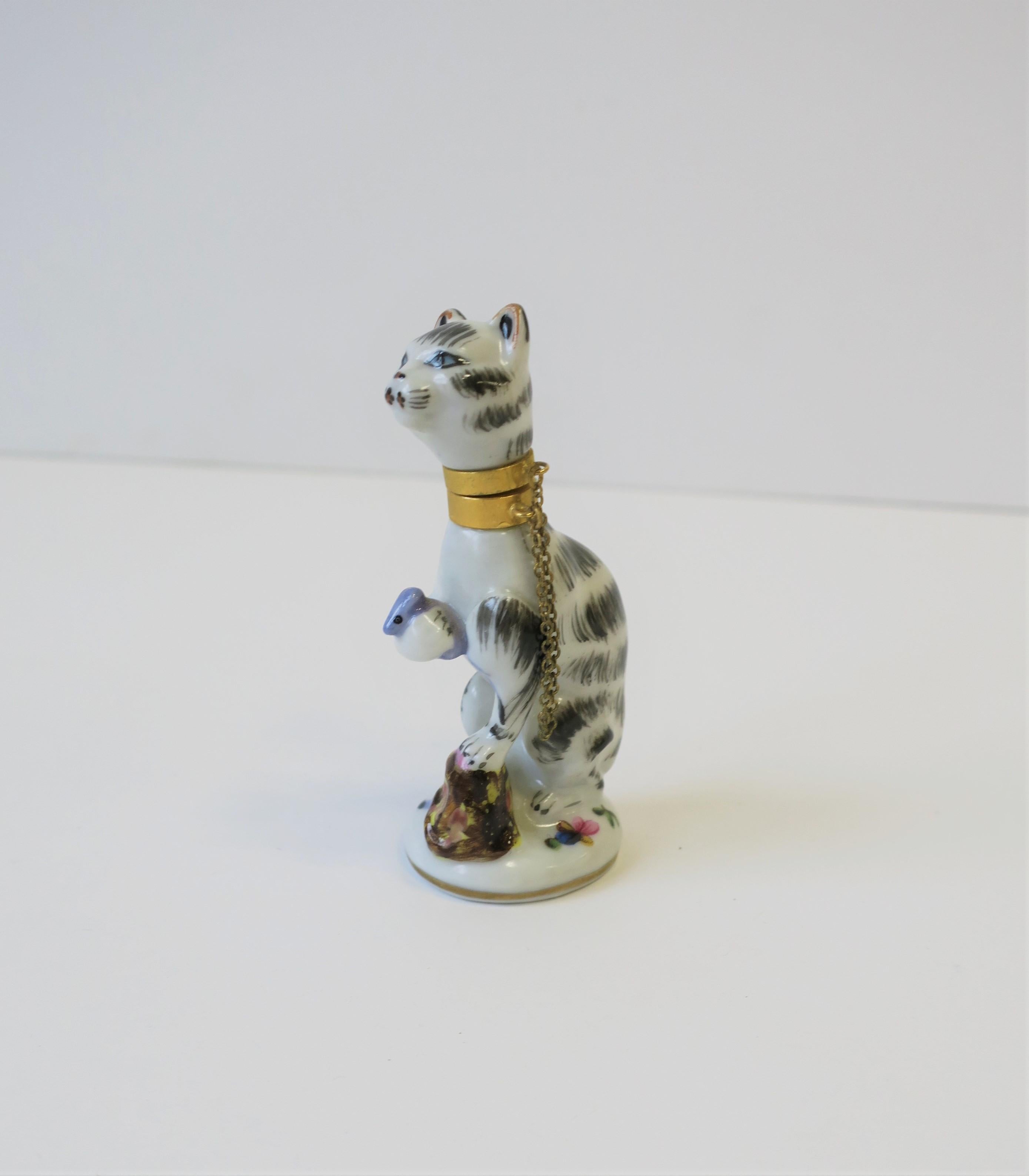 A great cat and mouse porcelain perfume bottle with brass collar and removeable head, circa 20th century, Metropolitan Museum of Art, New York. Cat has a black and white coat, blue eyes and brass collar with chain. Cat is holding mouse in paw.