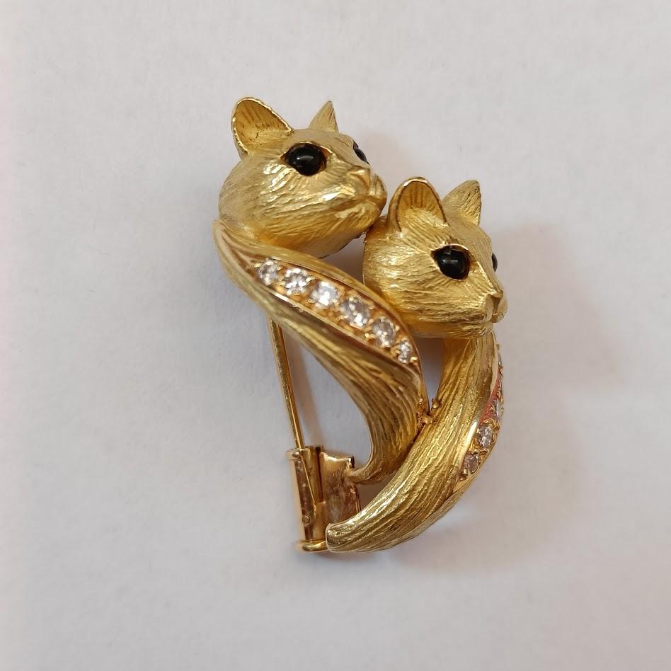 A brooch depicting two stylized cats in finely textured 18K yellow gold, adorned with onyx (the eyes) and brilliant-cut diamonds. Made by Jean and Pierre Bellin, France 1980s.

Signed J.P Bellin
Other small indistinguishable marks
Good condition, no
