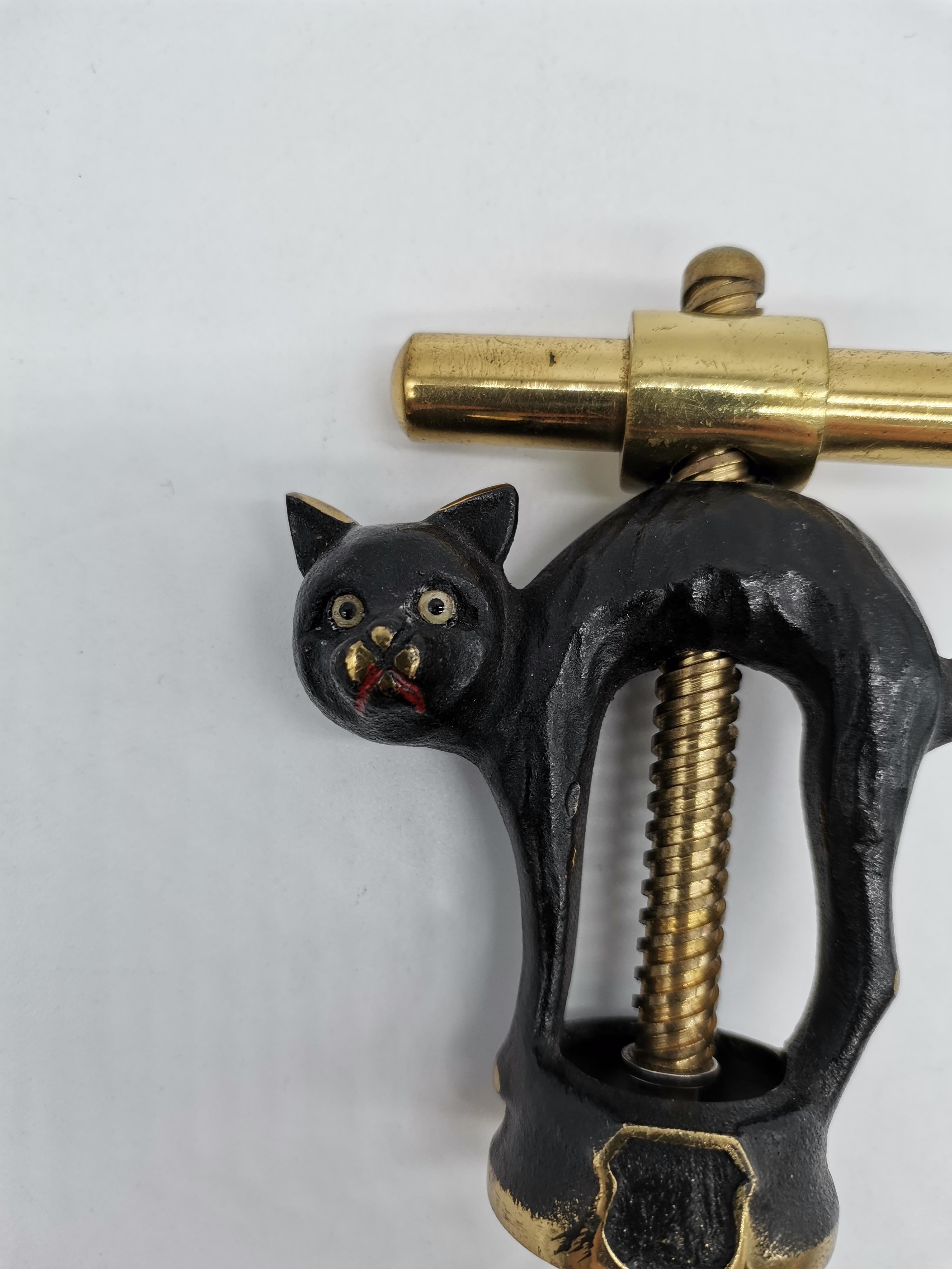 A cork screw in the shape of a cat by Walter Bosse made of partially blackened brass.
  
