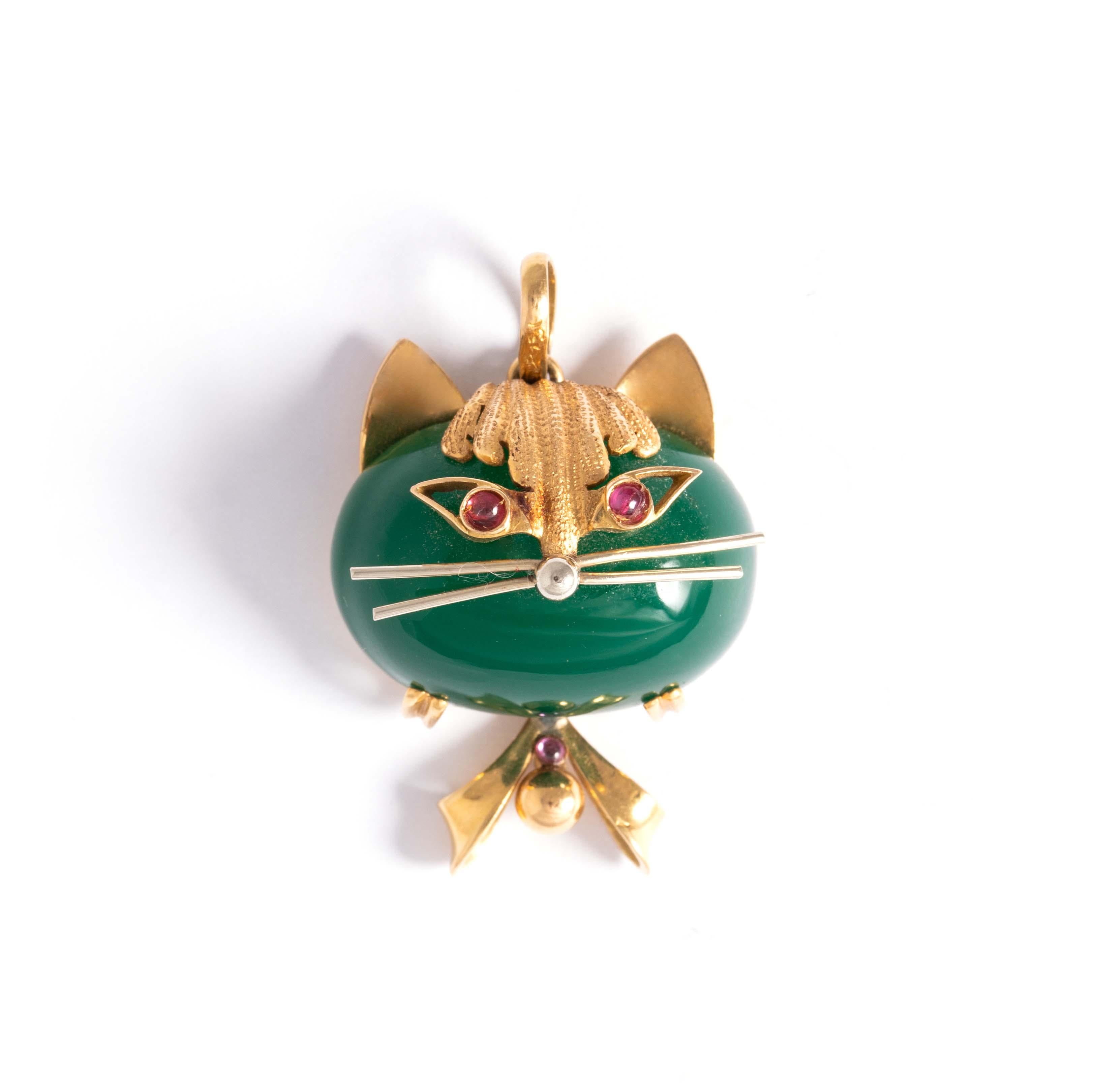 18K gold pendant representing a cat and holding a green cabochon stone. The eyes respectively set with a red cabochon stone.
Dimensions: 3.70 centimeters x 2.50 centimeters. 
Gross weight: 13.73 grams.