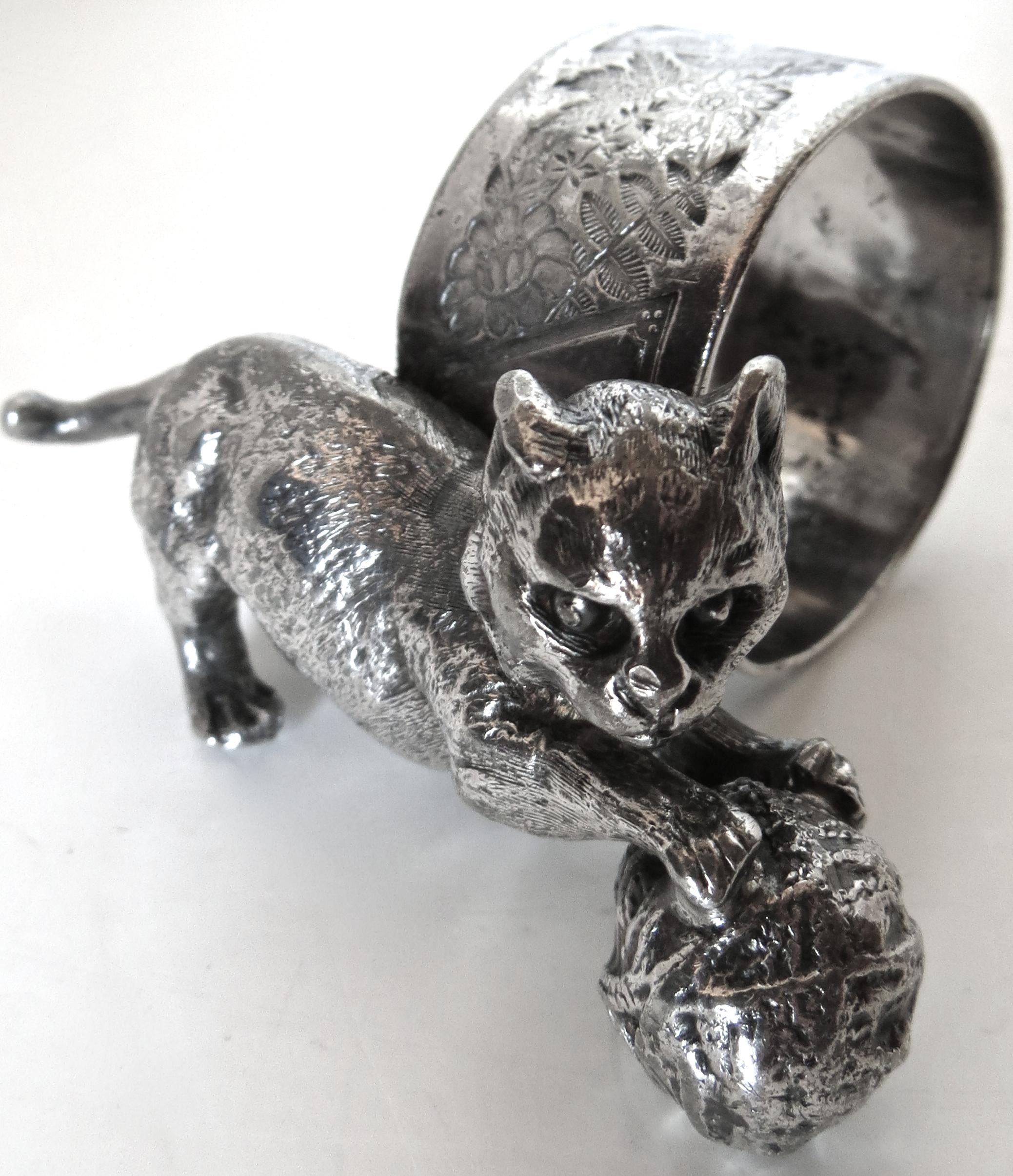 Animal themed Victorian napkin rings are sought after by collectors, perhaps because they remind them of pets they have; this particular ring depicts a cat whimsically playing with a ball of yarn, thus the name 