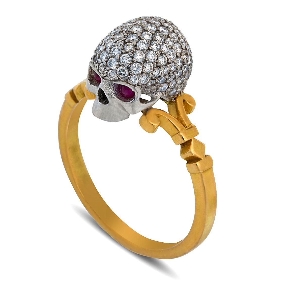 Handcrafted in 18kt yellow and white gold, this show-stopping ring features a baroque style diamond encrusted 18kt white gold skull with piercing ruby eyes perched atop a signature scrolled William Llewellyn Griffiths split shank. 

Measuring 9.5mm
