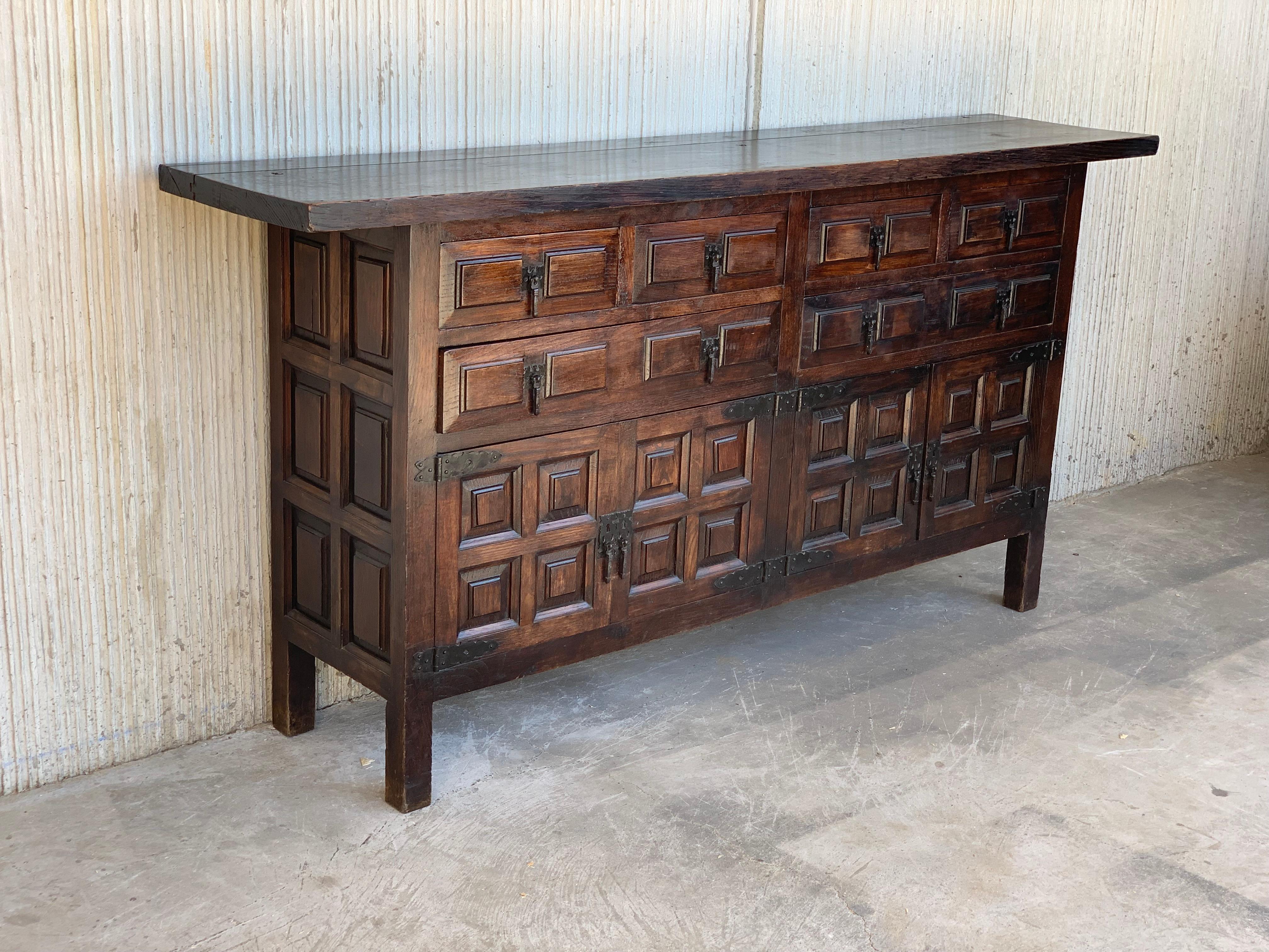 From Northern Spain, constructed of solid walnut, the rectangular top with molded edge atop a conforming case housing six drawers over four doors, the doors panelled with walnut veneers, raised on a plinth base.

 