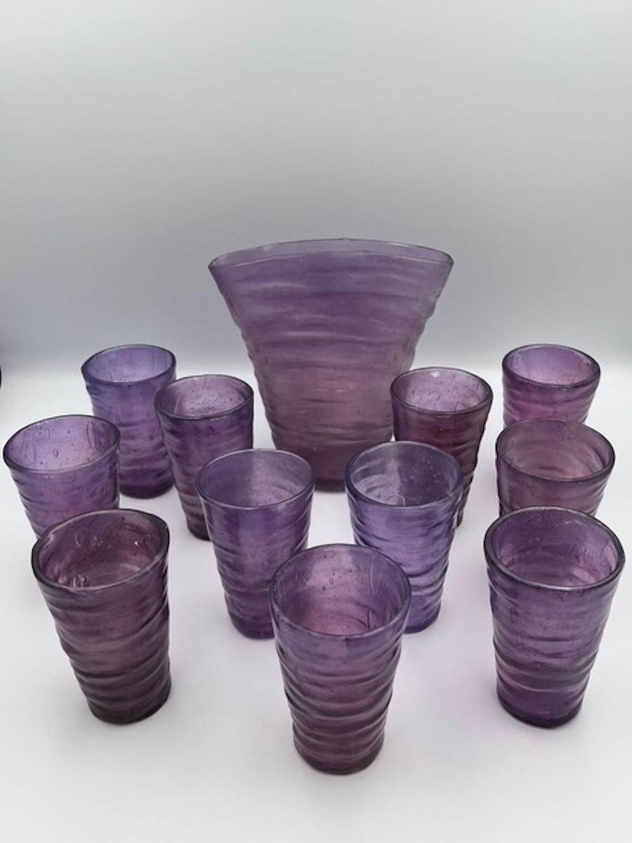 This exquisite vase and matching set of 11 juice glasses are a stunning example of the Catalina design by the Consolidated Glass Company of Coraopolis, Pennsylvania. Designed by the visionary Rubin Haley—best known for his bold and avant-garde Ruba