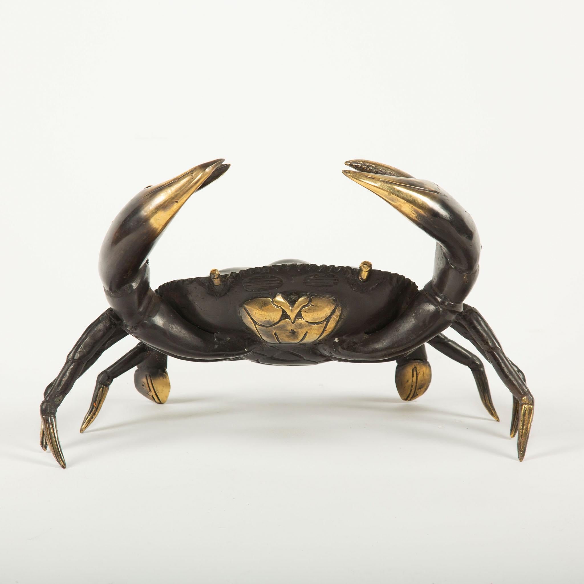 Una straordinaria scultura di granchio in ottone di grandi dimensioni, realizzata in modo naturalistico con zampe, chele e guscio finemente dettagliati. Il pezzo presenta un corpo patinato scuro con riflessi dorati a contrasto sulle chele, sulle