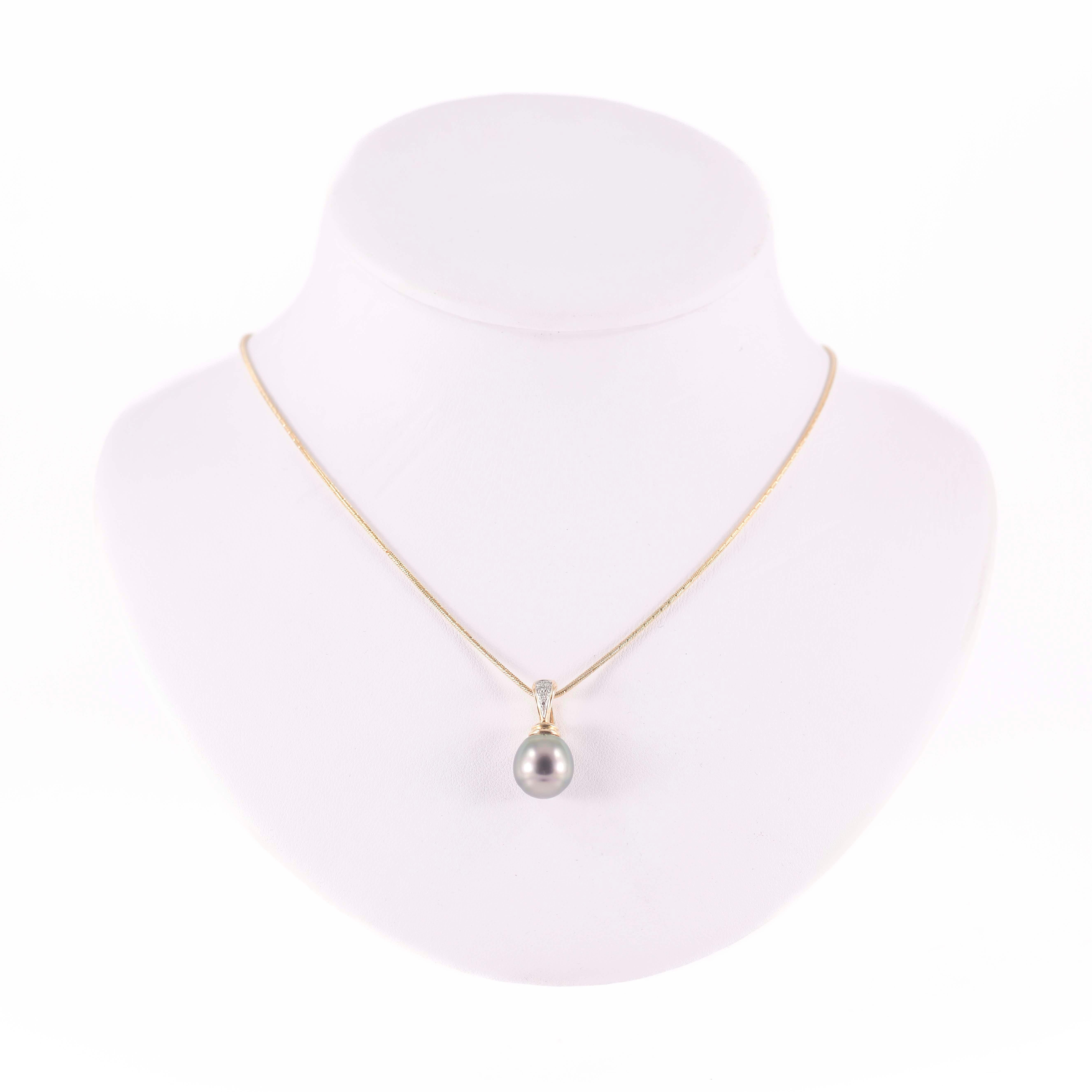 Collier en or jaune et blanc 18 carats - 750/1000, marqué '750', composé d'une chaîne fine et d'une perle grise  surmonté d'un anneau d'ouverture orné de petits diamants.
Le poids total de l'objet est de 11,97 grammes.
une description détaillée des