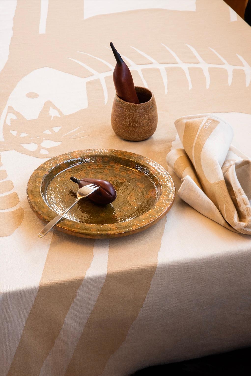 With this cotton tablecloth featuring our special cat/fish design, Viso offers you the loveliest dining experience. Woven in soft tan and light beige out of the finest Italian threads, this table setting compliments any space, either inside or