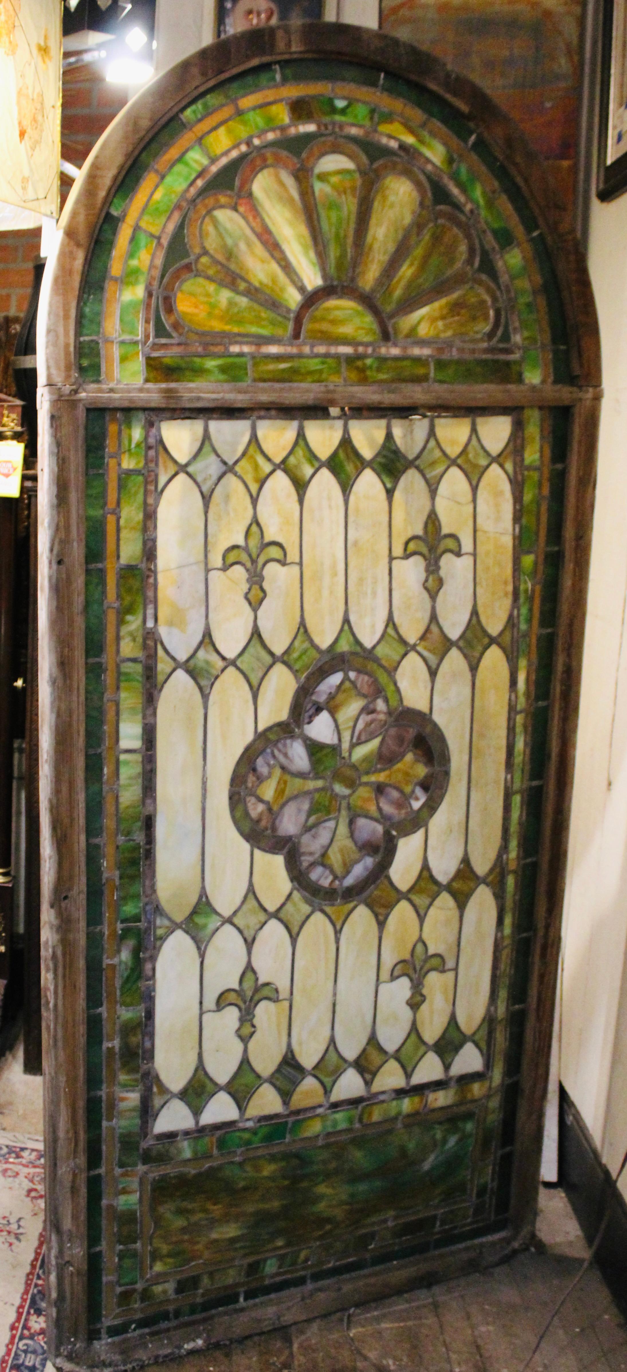 Fenêtre en dôme exquise avec des motifs de vitraux complexes. Sauvée d'une cathédrale avant sa démolition, cette fenêtre en deux parties montre son histoire à travers des carreaux de verre colorés. Verre de couleur vert marbré avec la croix au