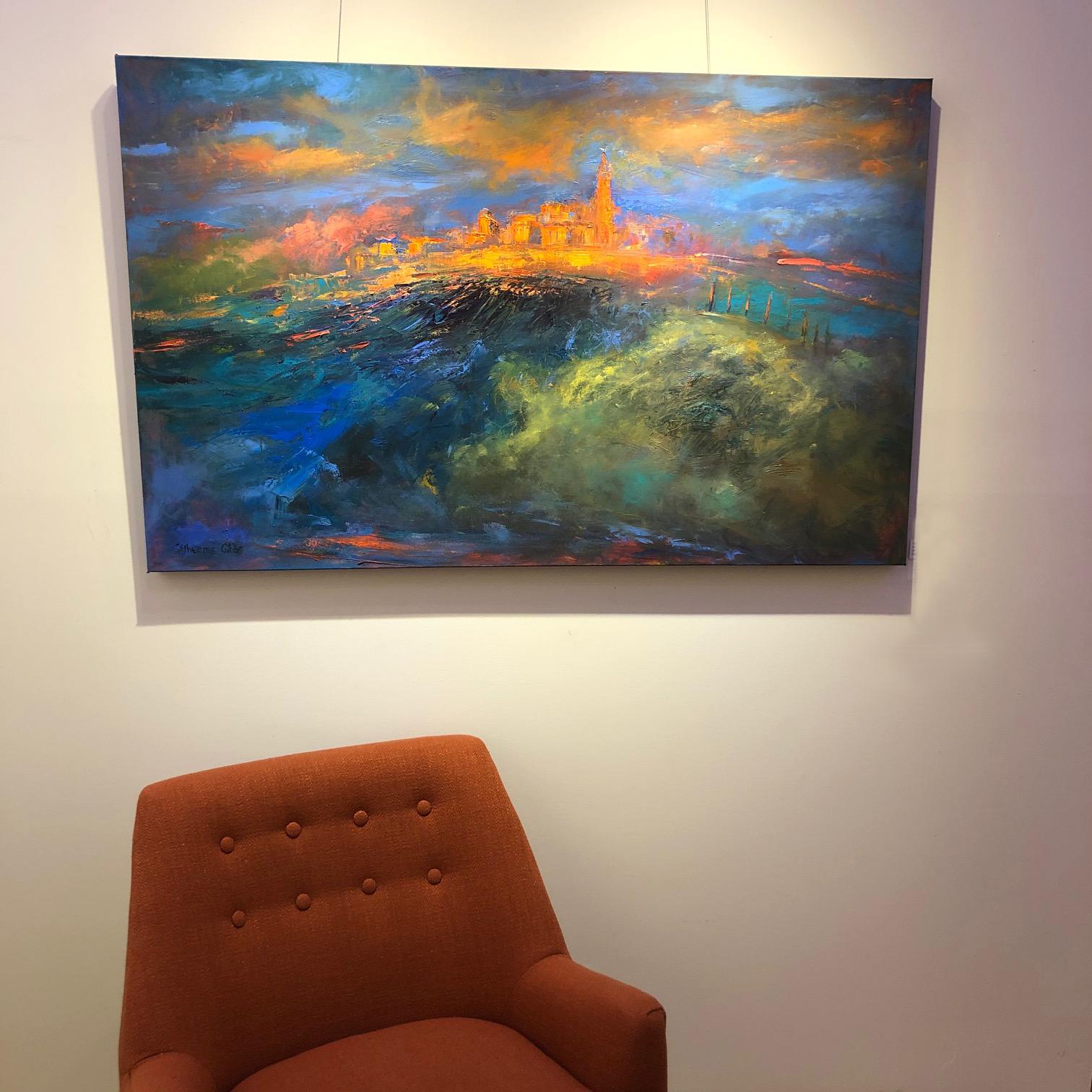 “City of Light” by Catherine Picard-Gibbs is a contemporary panoramic city landscape, painted in deep blues and greens which contrast with the textural golds, oranges, and reds. This dynamic 30 x 48 x 1.5 inch oil on canvas painting suggests the