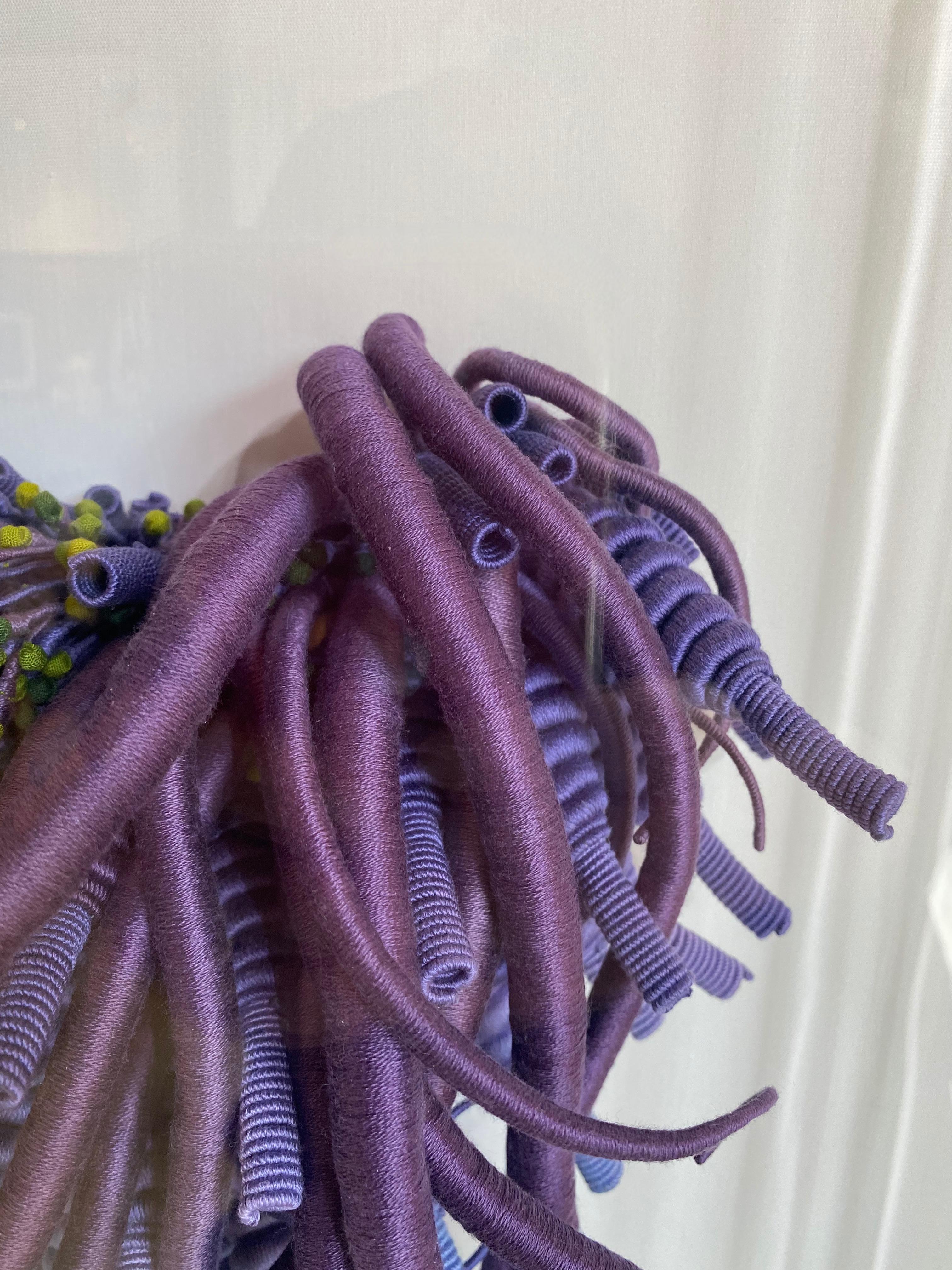 Esta escultura contemporánea de fibra montada en la pared, Espécimen 24, parece una interpretación artística de un bello espécimen marino. Un rico hilo de algodón teñido a mano en tonos púrpura joya envuelve unos zarcillos que se extienden desde un