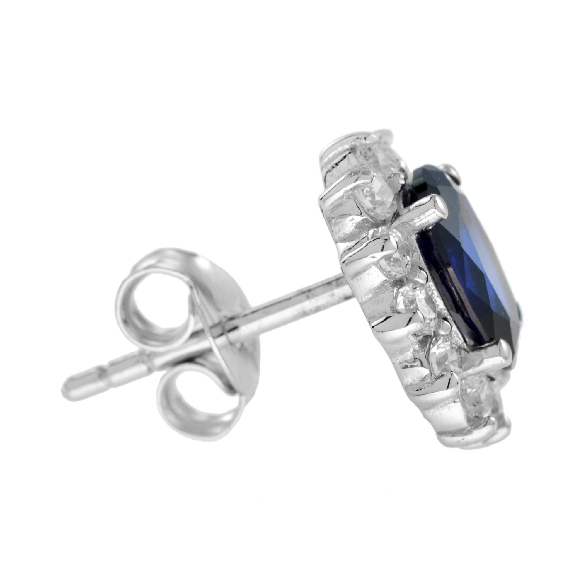 A pair of oval sapphire and diamond cluster earrings, each earring comprising an oval sapphire surrounded by twelve round brilliant cut diamonds, all claw set to 18K white gold. 

Information
Style: Vintage
Metal: 18K White Gold
Width: 11