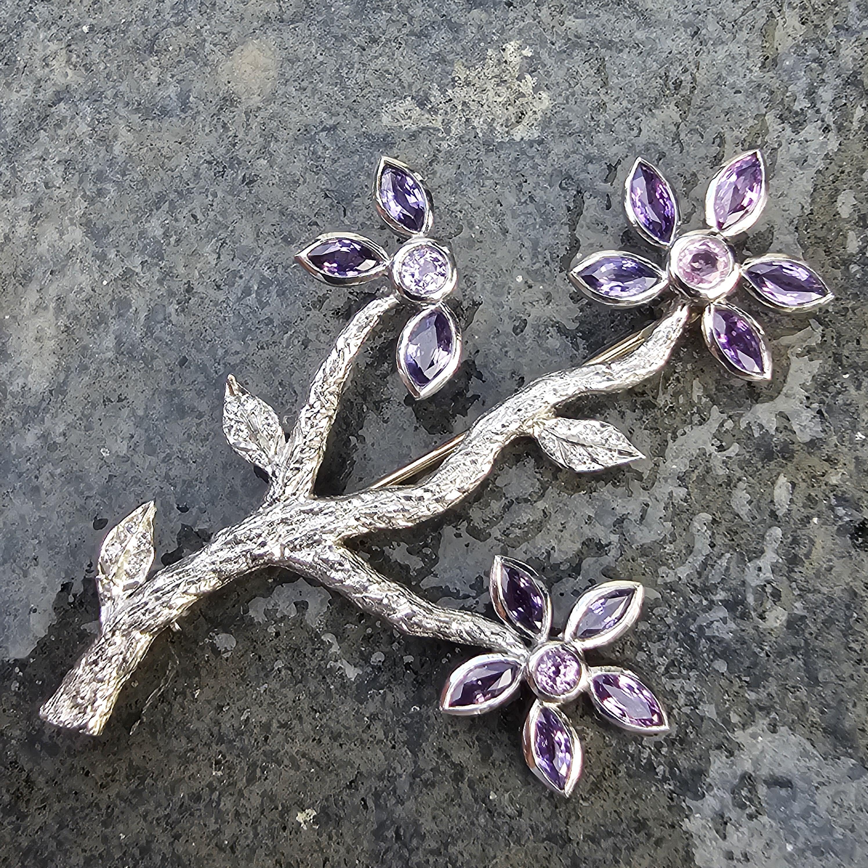 Eleva la tua collezione con questa splendida spilla di Cathy Waterman. Realizzato in platino, questo pezzo presenta un delicato disegno floreale. La spilla presenta vibranti zaffiri viola come petali, completati da scintillanti diamanti bianchi al