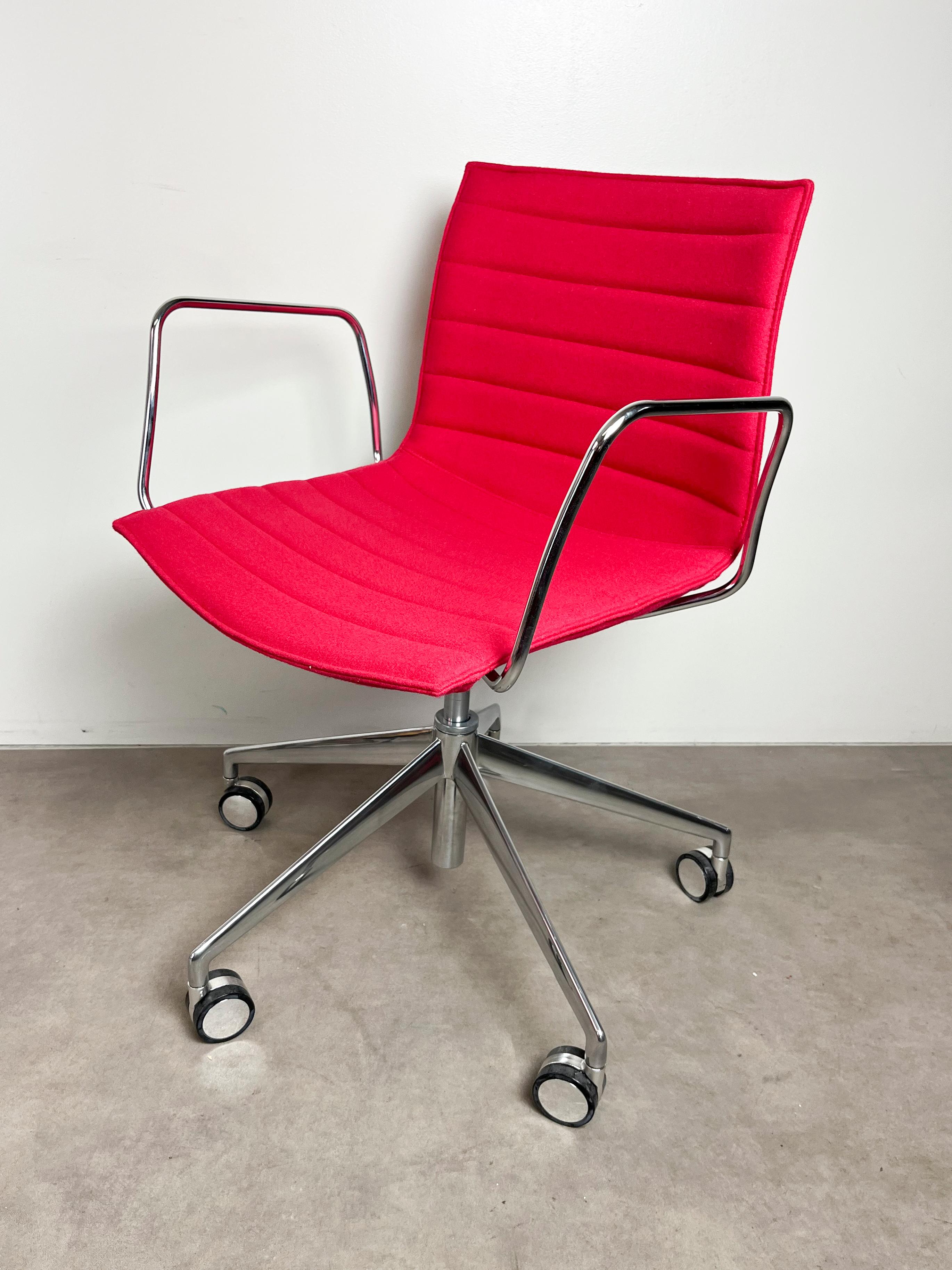 The Catifa 46 swivel chair, designed by Lievore Altherr Molina for Arper in 2004, features a base with 5 spokes and wheels for mobility. It is upholstered in pink Kvadrat Divina fabric, with a base in polished die-cast aluminium and polished steel