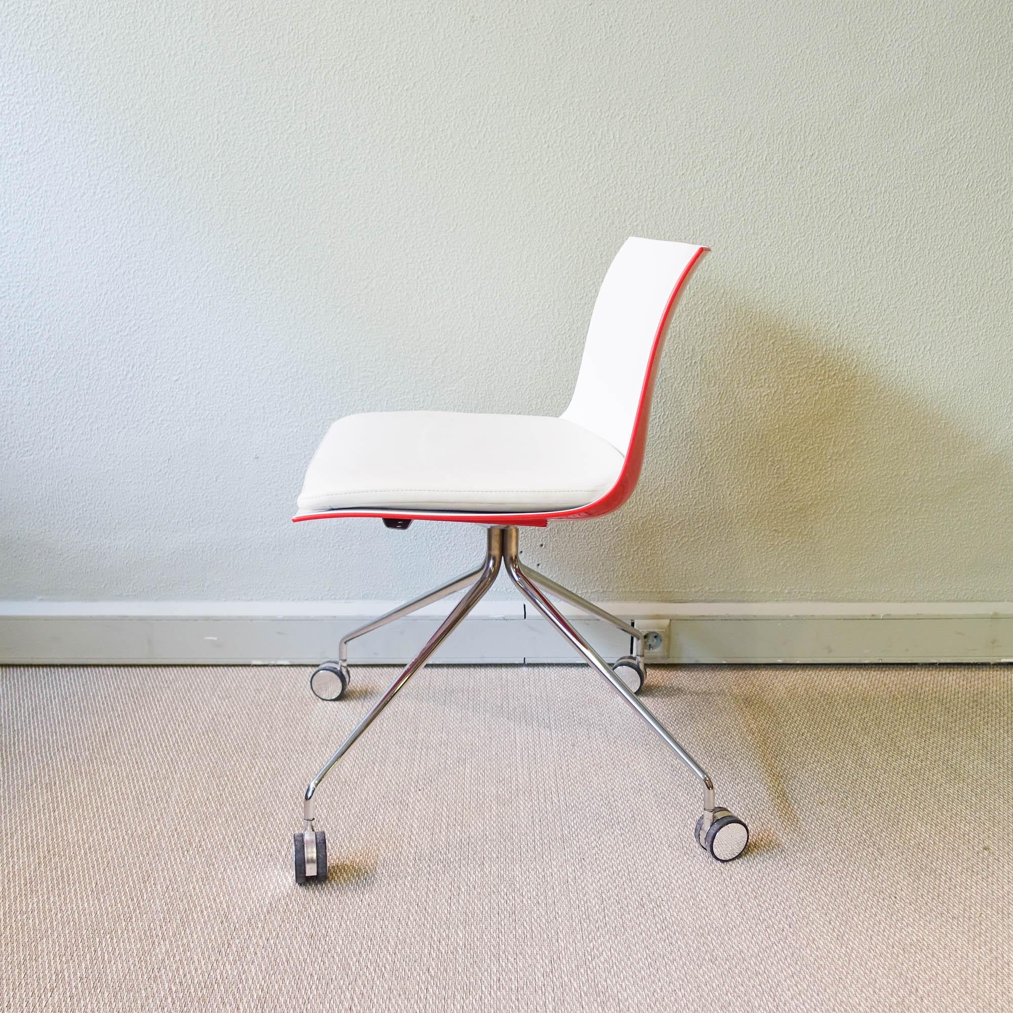 Cette chaise, modèle Catifa, a été conçue par Lievore Altherr Molina, pour  Arper, en Italie, en 2004.  Il est doté d'une coque bicolore en polypropylène, rouge à l'extérieur et blanc à l'intérieur, qui repose sur quatre pieds munis de roulettes en