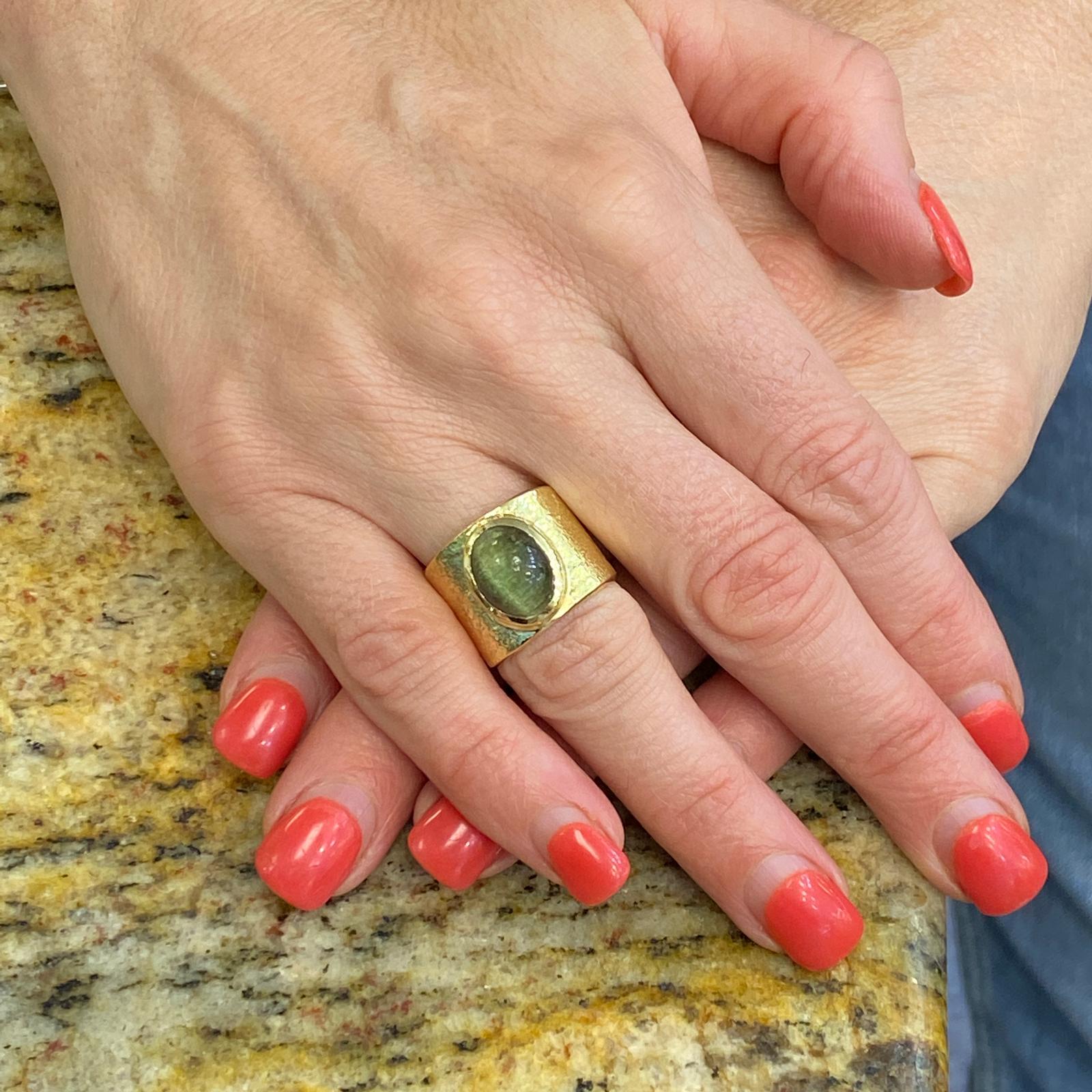 Fabulous Cat's Eye band ring handcrafted in 18 karat yellow hammer finished gold. The wide band measures 15mm in width and featuers an approximately 4 carat cat's eye bezel set gemstone. The band is 6 and signed Eveli.
