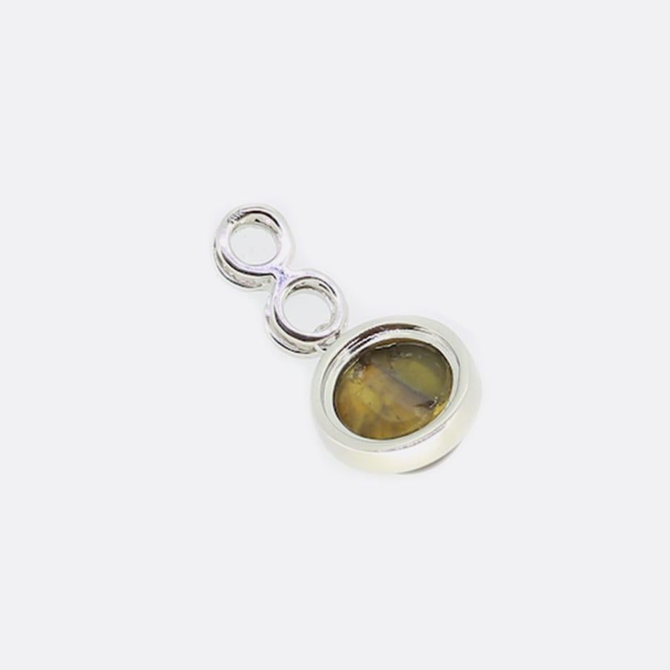 This is an 18ct white gold pendant. The top of the pendant is formed of a black diamond double halo and beneath it is a beautiful cats eye gemstone.

Condition: Used (Very Good)
Total Weight: 2.5 grams
Pendant Dimensions:21mm x 10mm x 5mm
Black