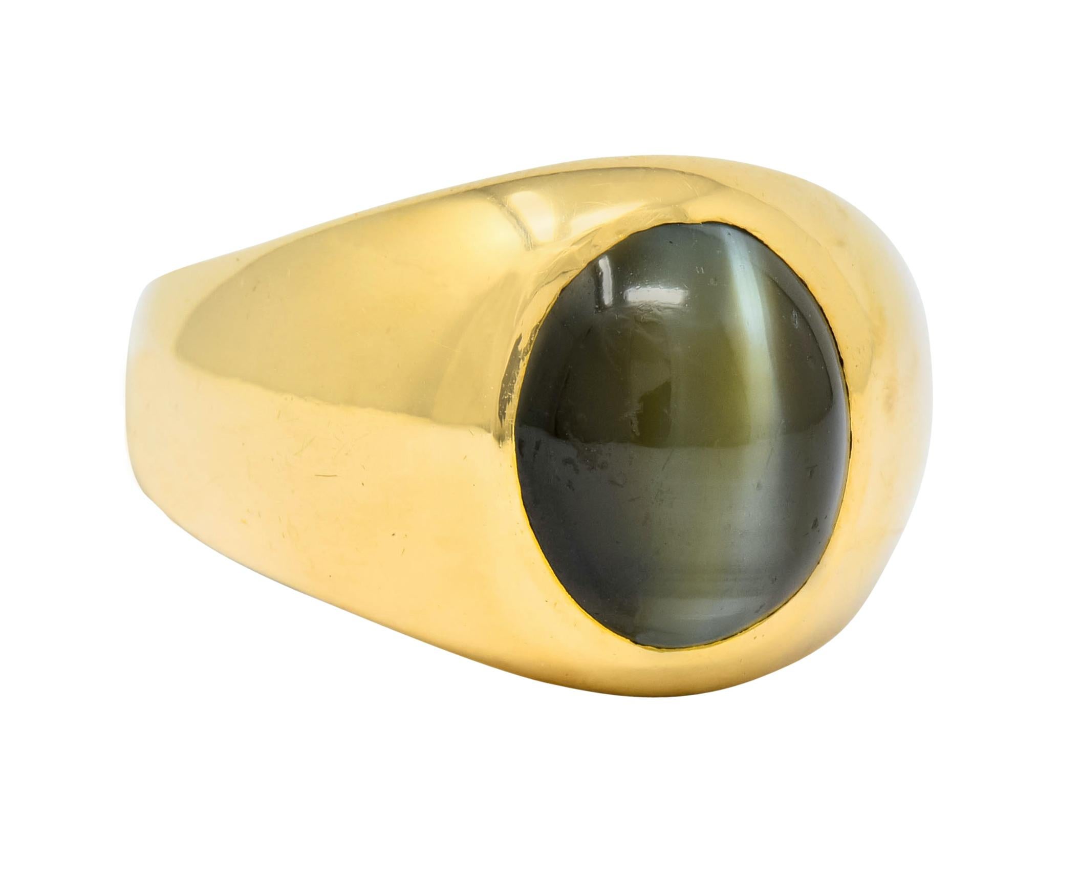Centering an oval cabochon cat's eye, measuring approximate 11.3 x 9.5 mm

Cat's eye with deep slightly yellowish green with a straight, distinct eye and milk & honey effect

Flush set in high polished gold

Stamped 18K

Ring Size: 7 1/4

Top