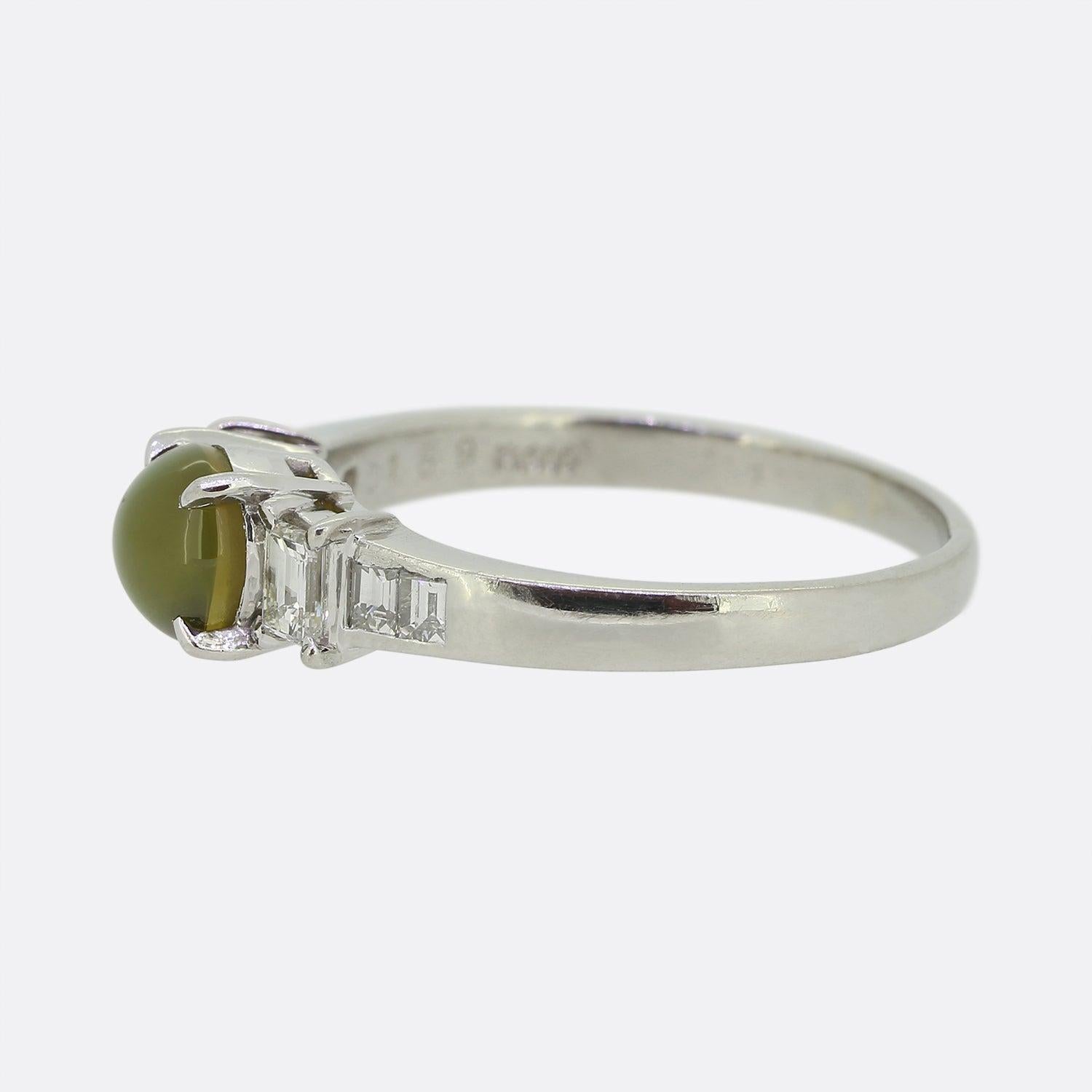 Here we have a wonderful chrysoberyl and diamond ring. This piece has been crafted from platinum and showcases a single cat's eye chrysoberyl gemstone which sits proud at the centre of the face and possesses a lovely honey green colour tone. This