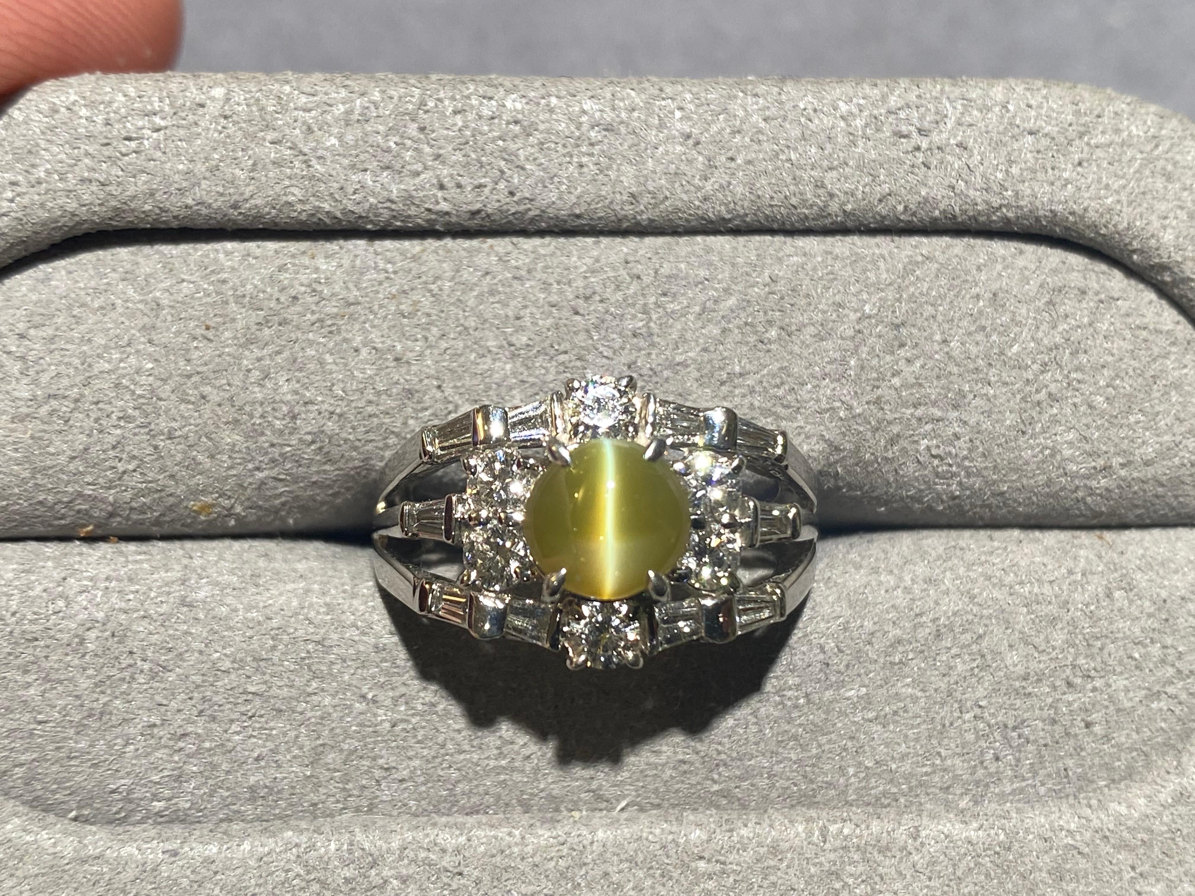 A Cat's Eye Chrysoberyl and diamond ring in 18k white gold. The chrysoberyl is in greenish honey colour with good translucency. The Chatoyancy effect of this stone is sharp and clear which is highly desirable. The chrysoberyl is then surrounded by 6