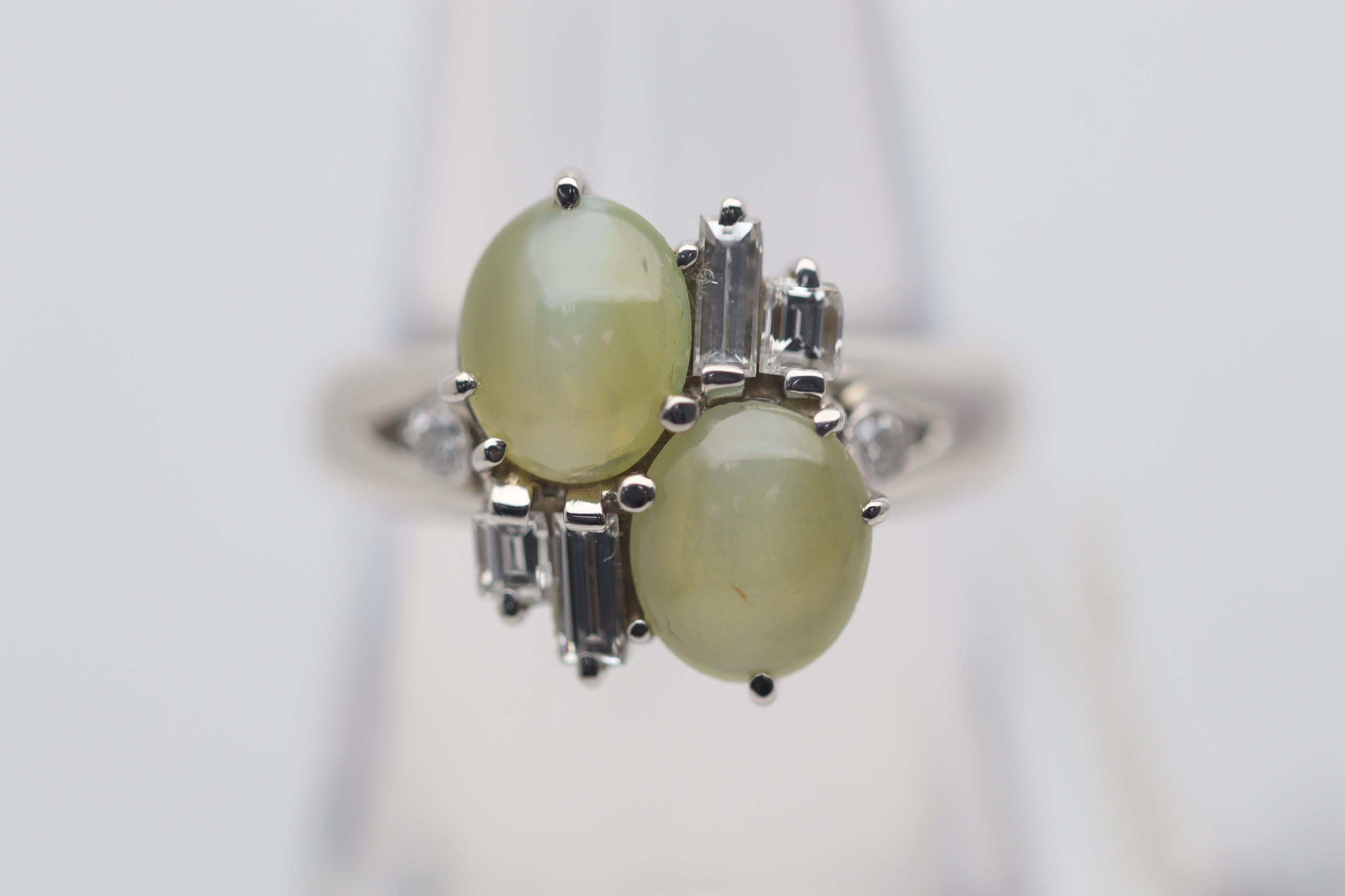 A fine and stylish ring featuring a pair of cats eye chrysoberyl. They are perfectly matching in their fine “milk & honey” color along with their strong chatoyant cats eye. They weigh a total of 2.62 carats and are complemented by 6 diamonds