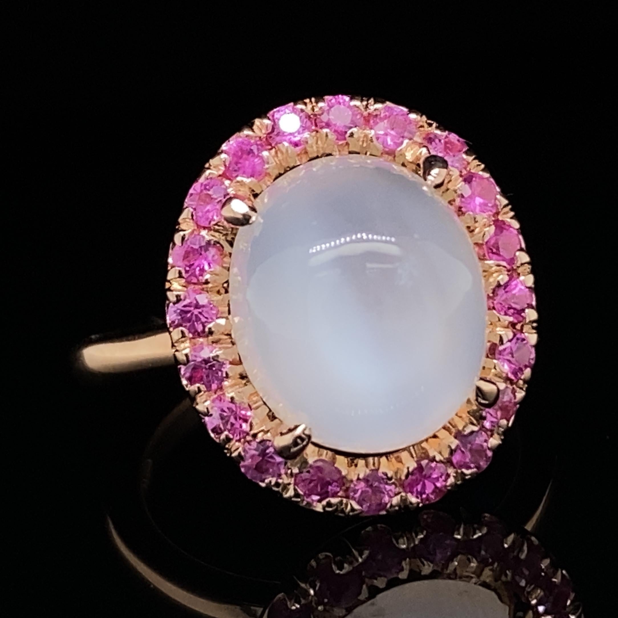 This gorgeous, cheerful ring by Eytan Brandes shows off a high-dome moonstone cabochon with exceptional chatoyancy.  The drama of the center stone really pops thanks to its halo of twenty vivid pink Burmese rubies and the unfussy rose gold mounting.