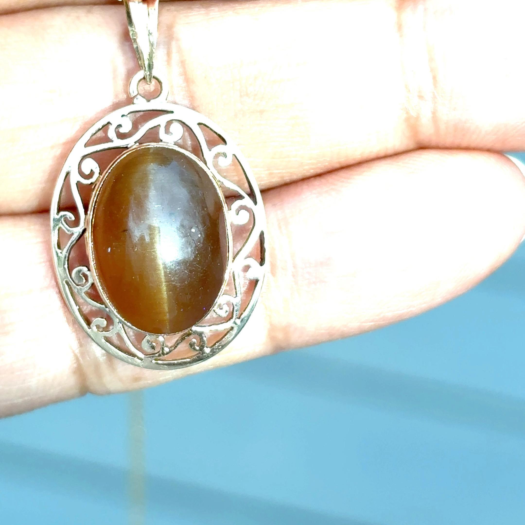 14K Yellow Gold Cat’s Eye Pendant with Jali Work
A captivating blend of tradition and elegance, this pendant showcases a honey-colored cat’s eye gemstone, renowned for its distinct, luminous band that glides across the surface. The center stone is