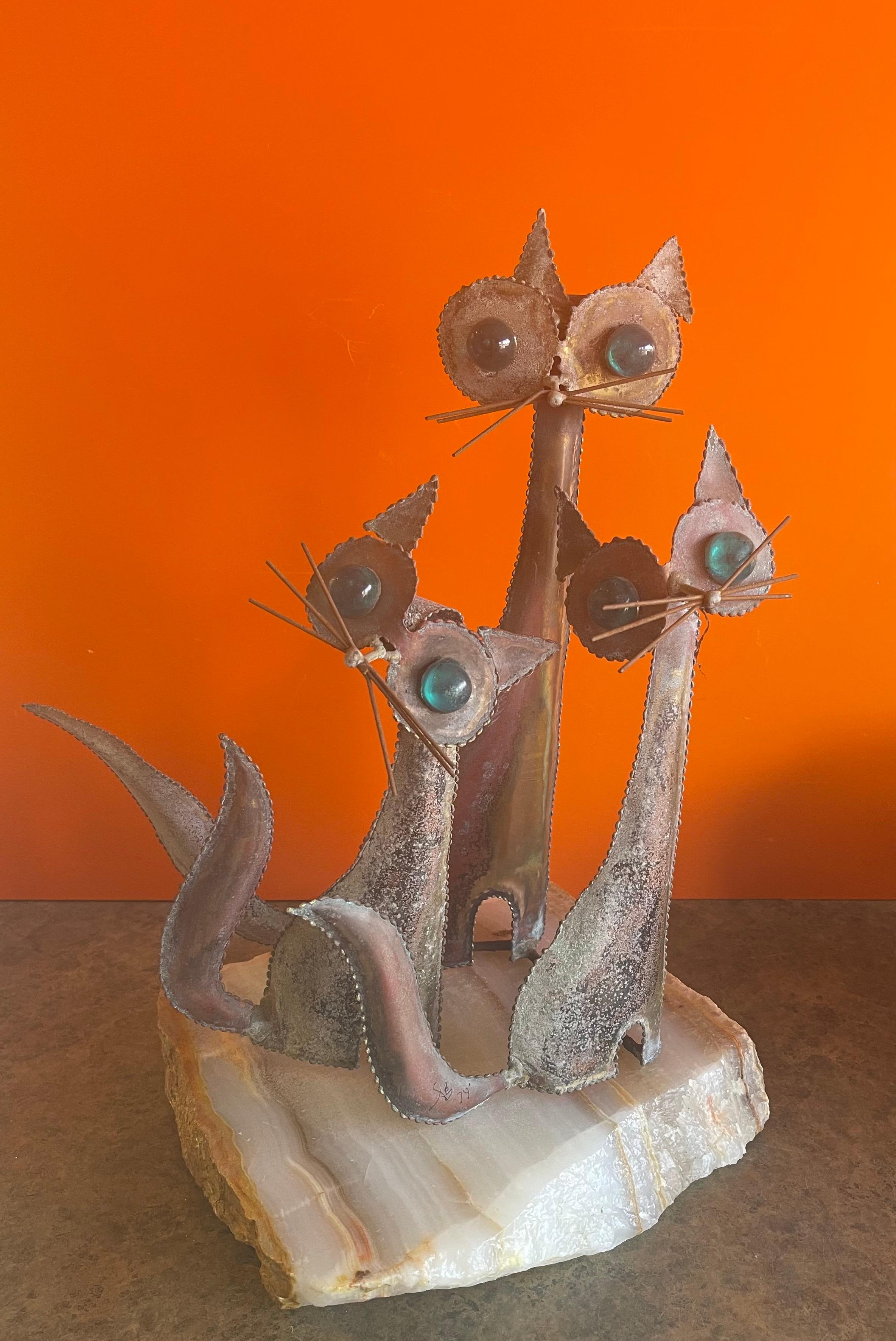 A very cool and rare cats sculpture on a solid block of white onyx in the style of C. Jere, circa 1974. The piece is signed and dated and has a wonderful patina. The cats eyes are a bright teal color that blends beautifully with he aged patina of