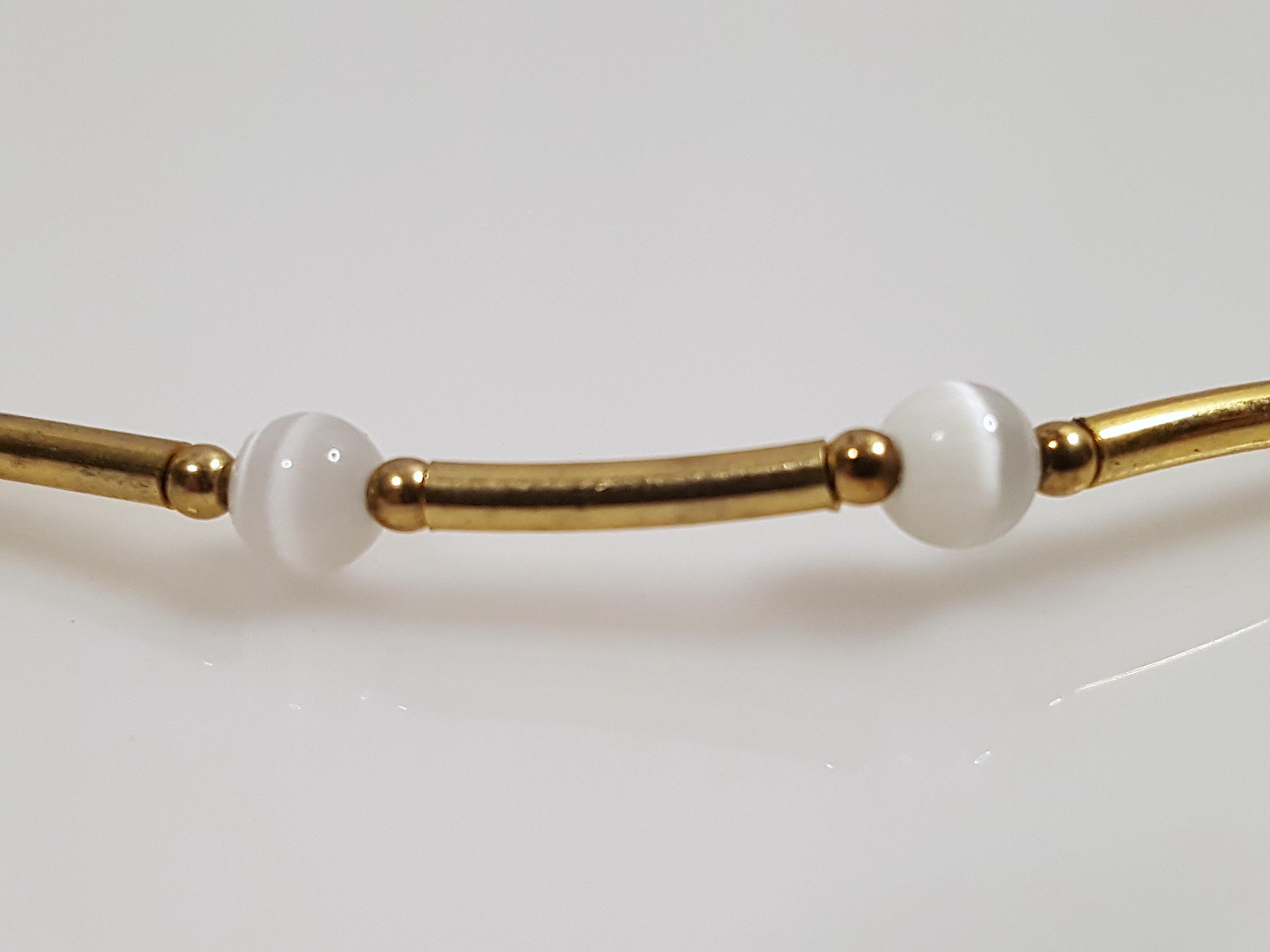 All featuring white cat's eyes, 21 gray 3mm ball-cut moonstones are beaded on this antique symmetrical choker necklace between stations of shiny 14-karat gold-filled tubes that are bracketed by gold ball spacers. Resembling modern minimal Cartier