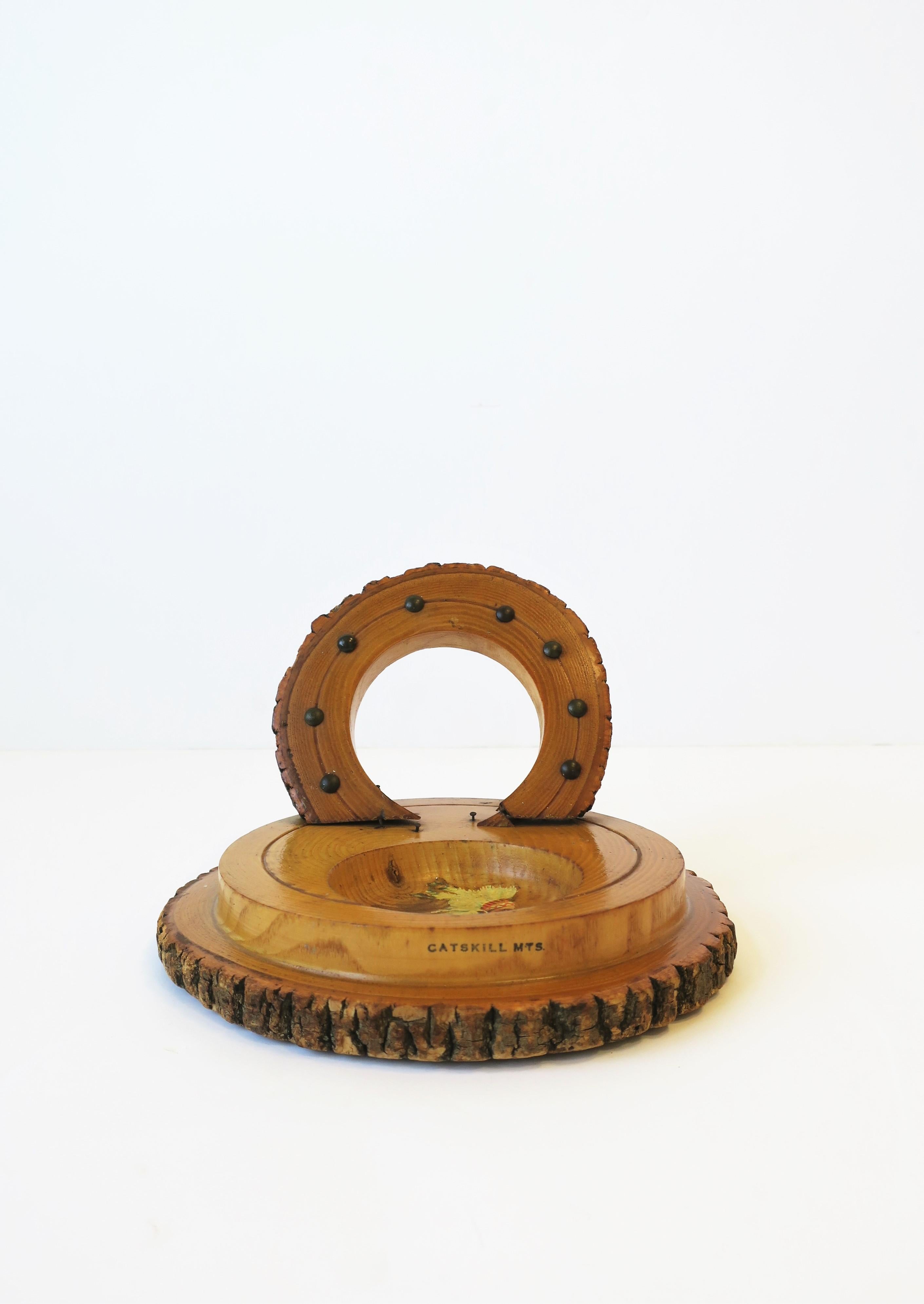 A 'Catskill Mountains' wood catch-all piece, circa mid-20th century, USA. Piece is hand carved of raw wood, varnished, with horseshoe design and metal detail, and round catchall space with Native American Indian design. Piece may work well on a desk