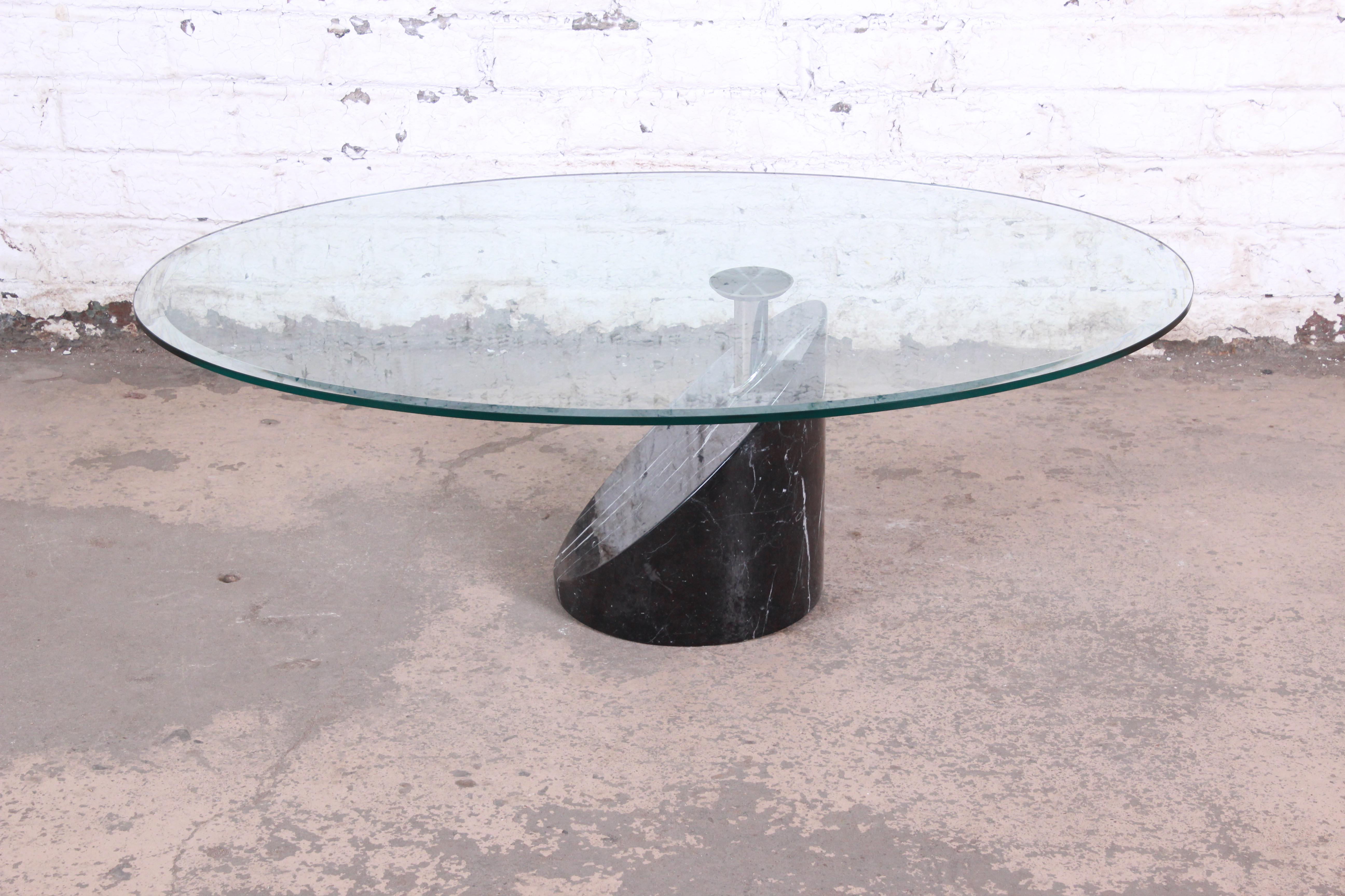 A gorgeous modern Italian marble, chrome, and glass coffee or cocktail table by Cattelan Italia. The table features a stunning heavy black marble base with white veining and an oval beveled glass top in a cantilevered design. The tabletop uniquely