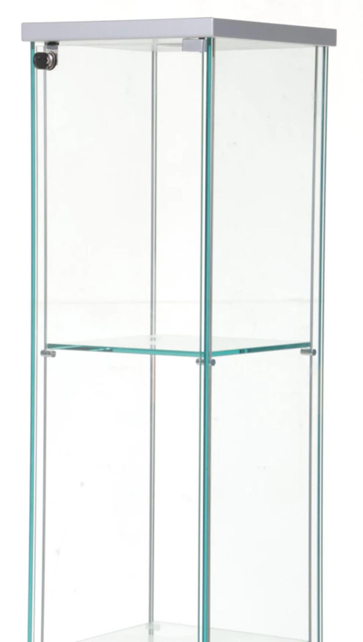 Tall and lighted display tower or vitrine by Cattelan Italia. All glass etagere with lock and  well hinged glass door and three removable glass shelves. Included is a key for the locked door. Desirable “blue” edge Italian glass. 