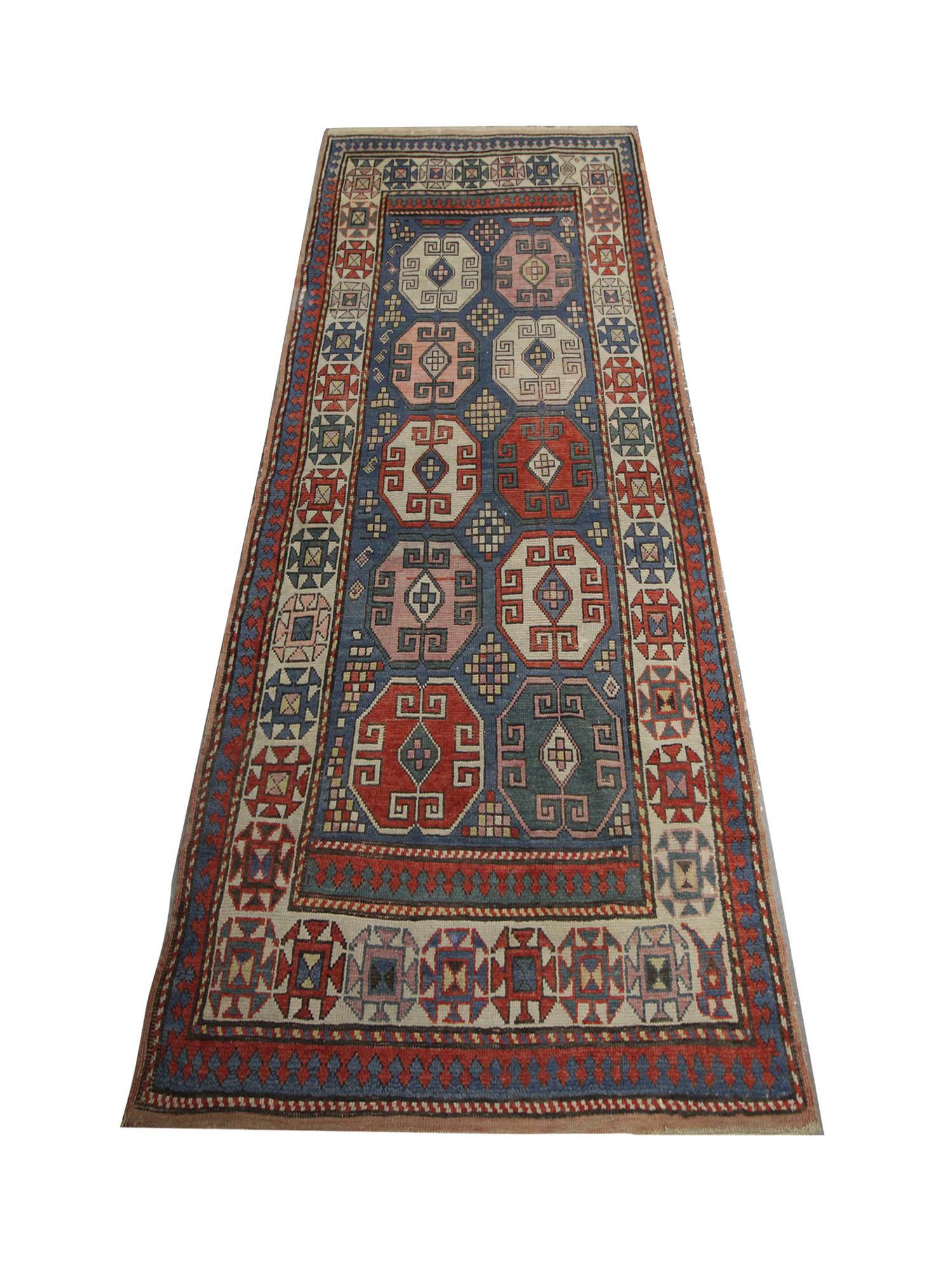 Ce tapis ancien du Caucase, tapis d'Azerbaïdjan, présente un design asymétrique. Le centre présente dix emblèmes octogonaux avec des motifs entrelacés sur un fond bleu entouré d'autres détails géométriques. Ce tapis oriental fait main est ensuite