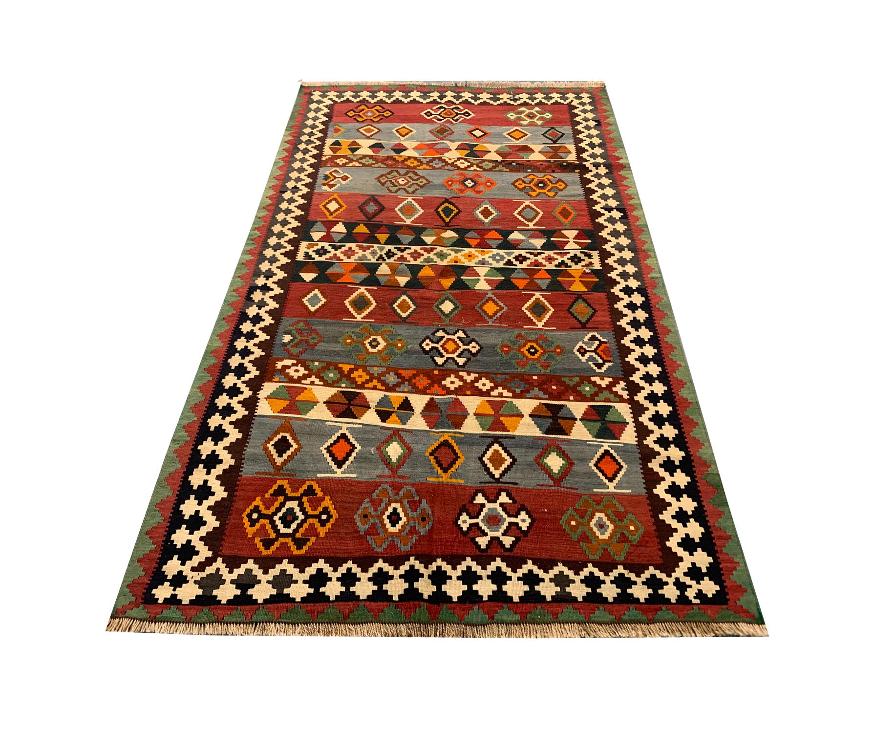 This bold geometric rug is an Antique piece. Woven by hand in the 1900s by Village weavers of Azerbaijan. The central design features a bold colour palette with rich red, rust, cream and blue accents that make up the stripe tribal motif design. Both