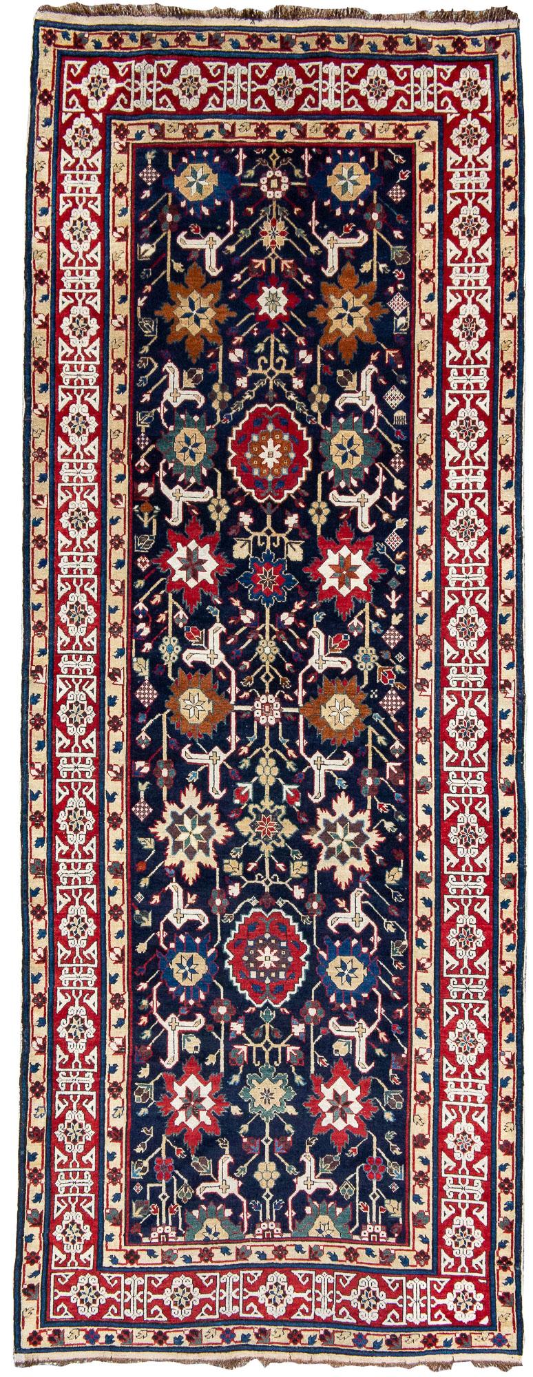 Woven in the east Caucasus near the Caspian coast, this Shirvan long rug uses perfect scale of drawing accentuated by vibrant saturated color. The field is composed of abstract floral ornament with a central column of varying rosettes flanked on