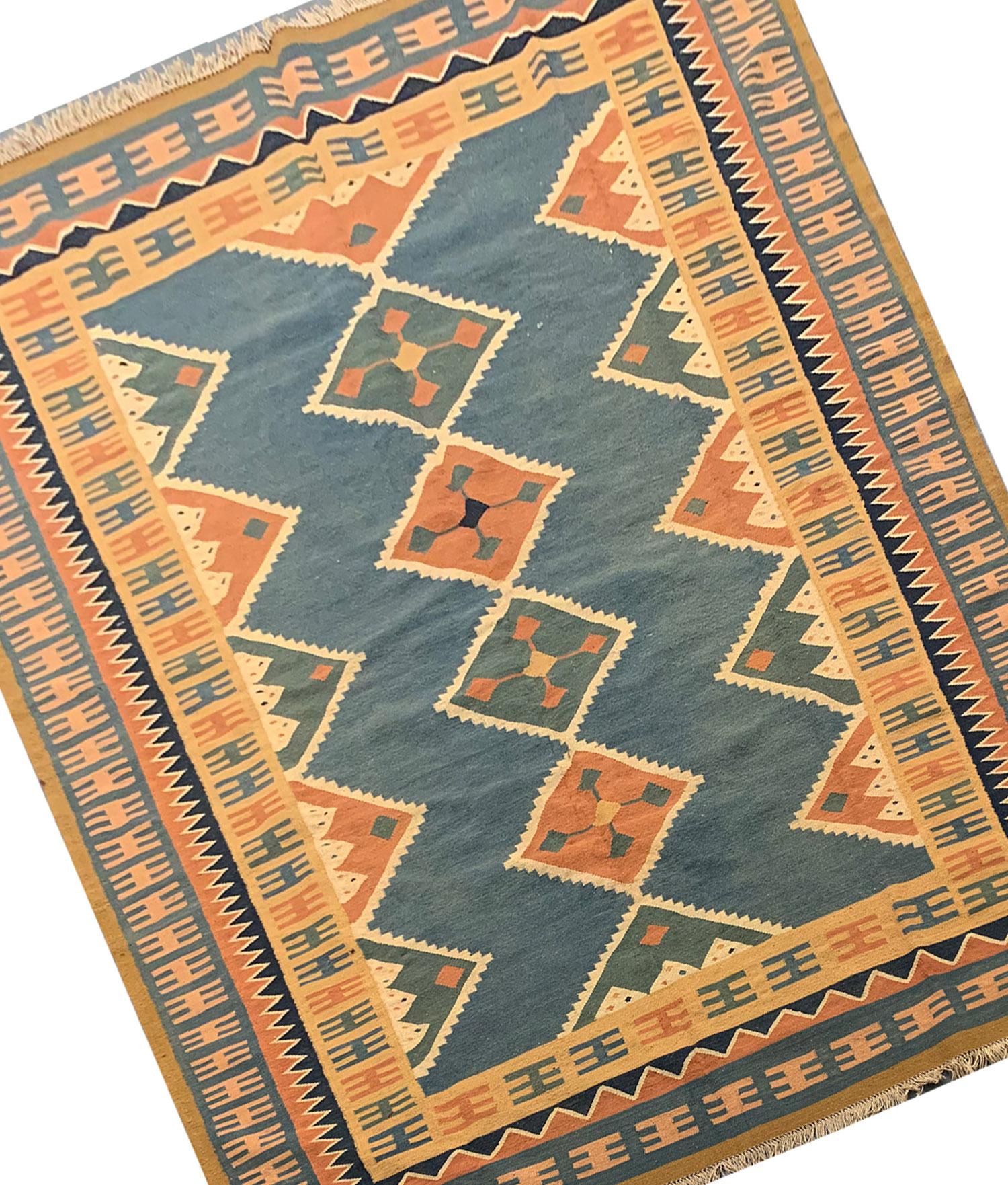 Blue, orange and cream make up the main accent colours in this simple, elegant vintage Kilim. Woven by hand in the 1940s by village weavers of Azerbaijan known for their finely woven village kilims. Featuring a bold geometric diamond design woven