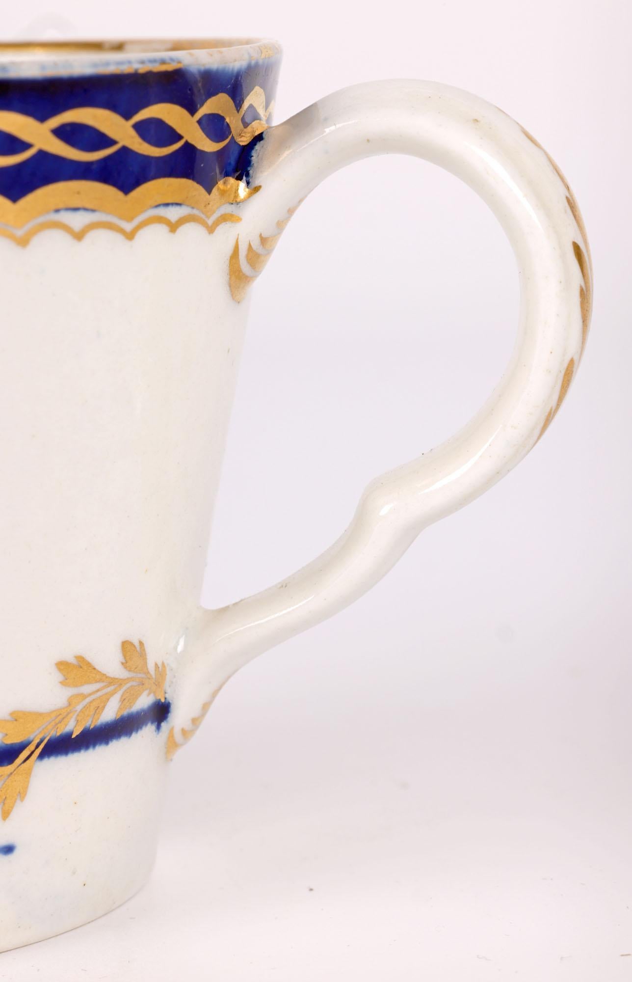 A scarce and fine antique English porcelain cream jug decorated with gilded patterning by Caughley and dating from around 1780. The pail shaped jug stands on a narrow round foot with a wide round top with a beak shaped pouring spout and ear shaped